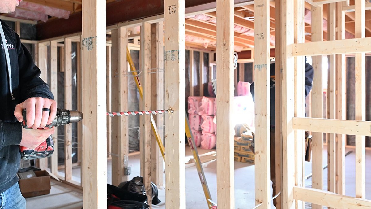 Drilling a hole through a wall stud to place electrical wires.