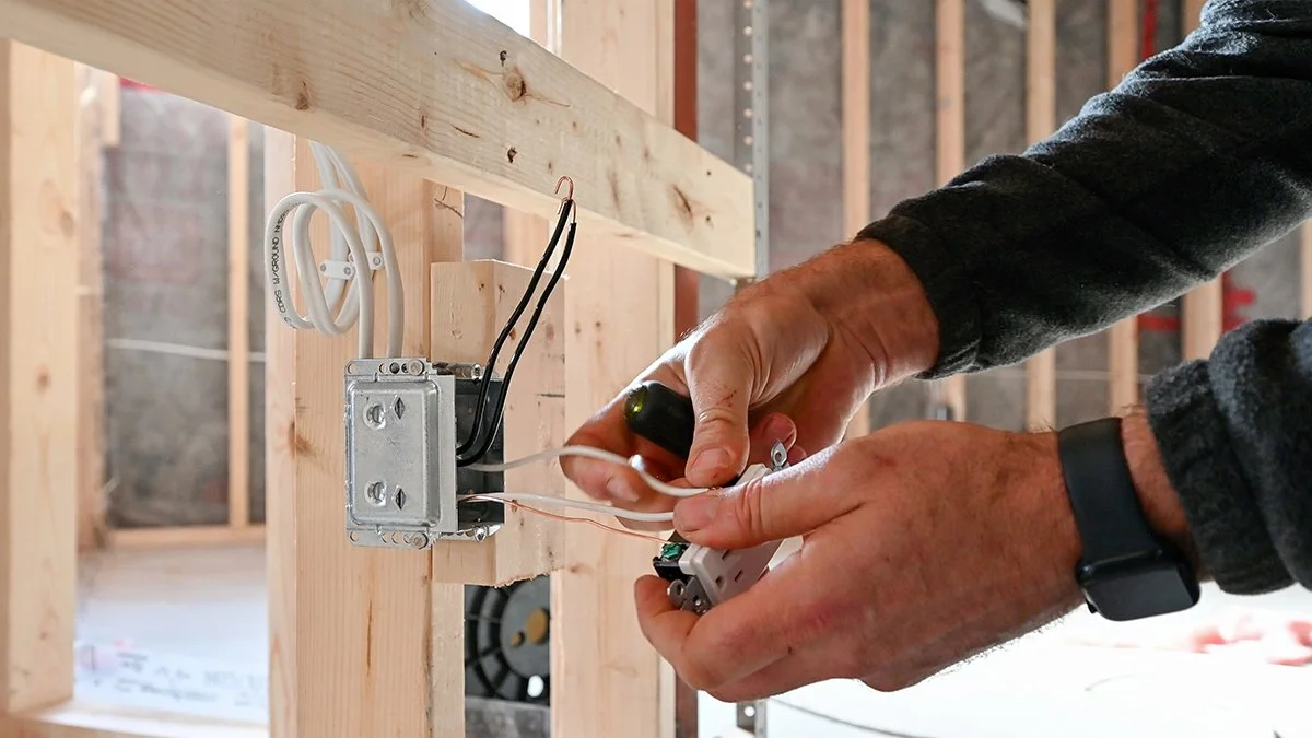 Electrician wiring a wall outlet.