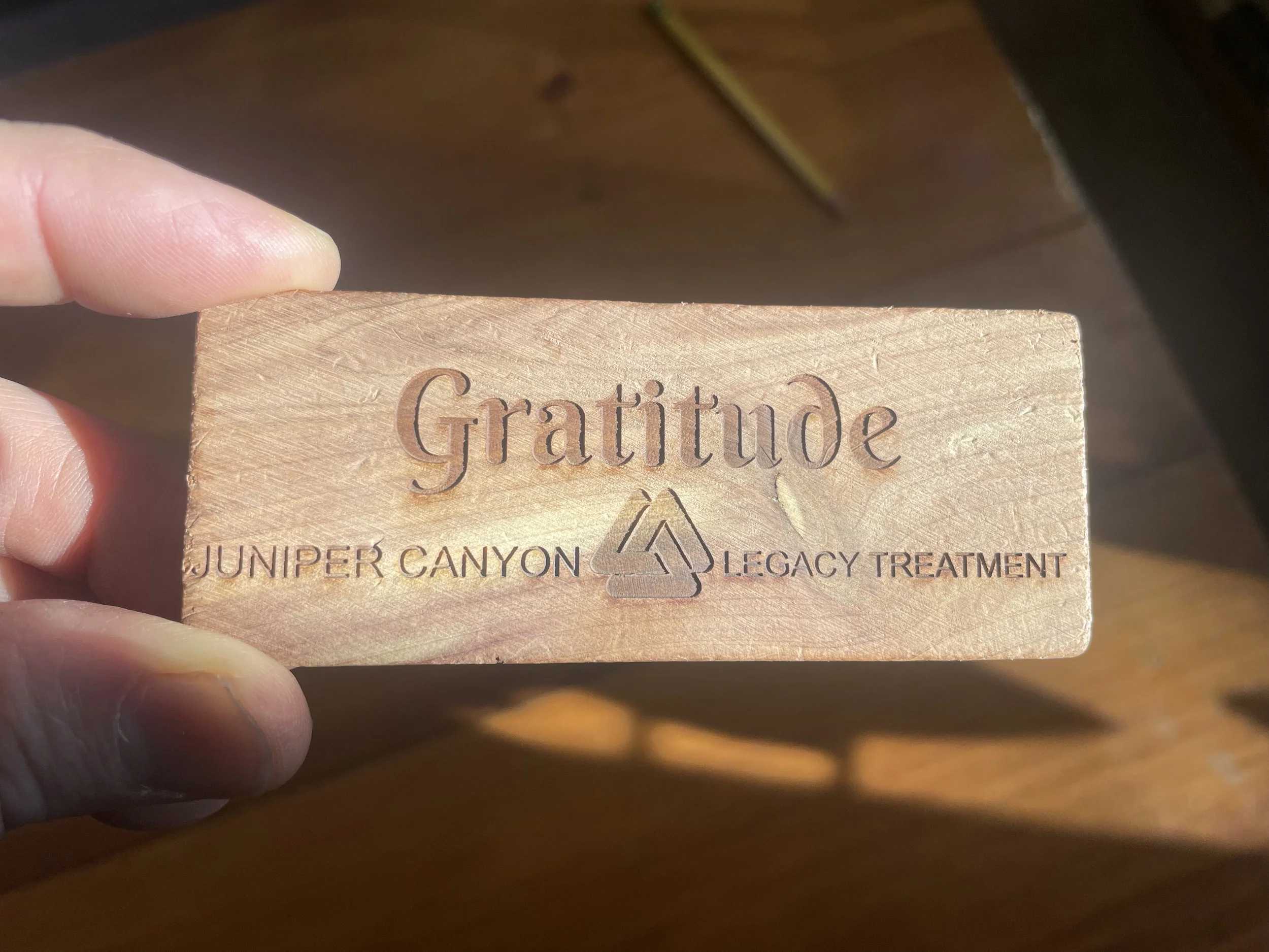 A small piece of carved red cedar with the word "Gratitude" carved in it