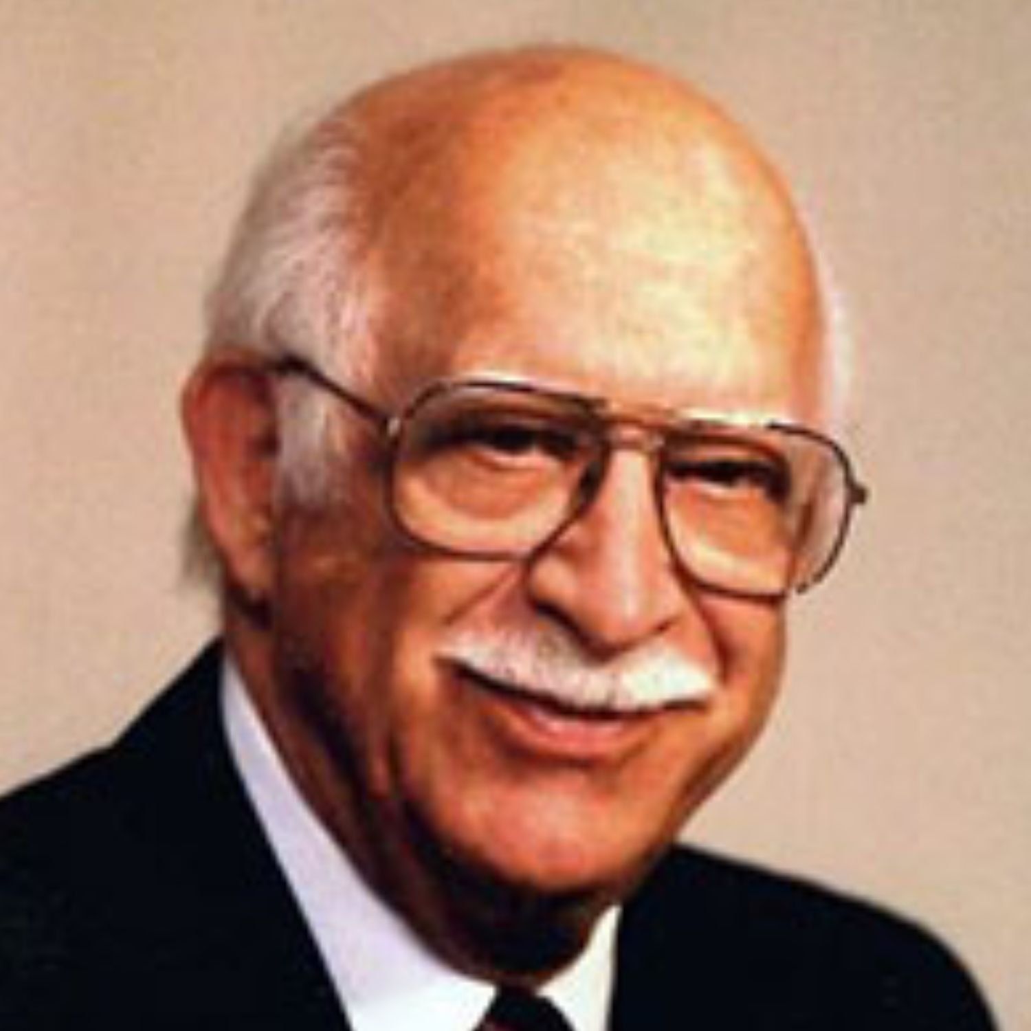 Portrait of Jimmie Saied (founder of Saied Music Company in 1946) with a mustache, glasses, wearing a suit and tie, smiling.
