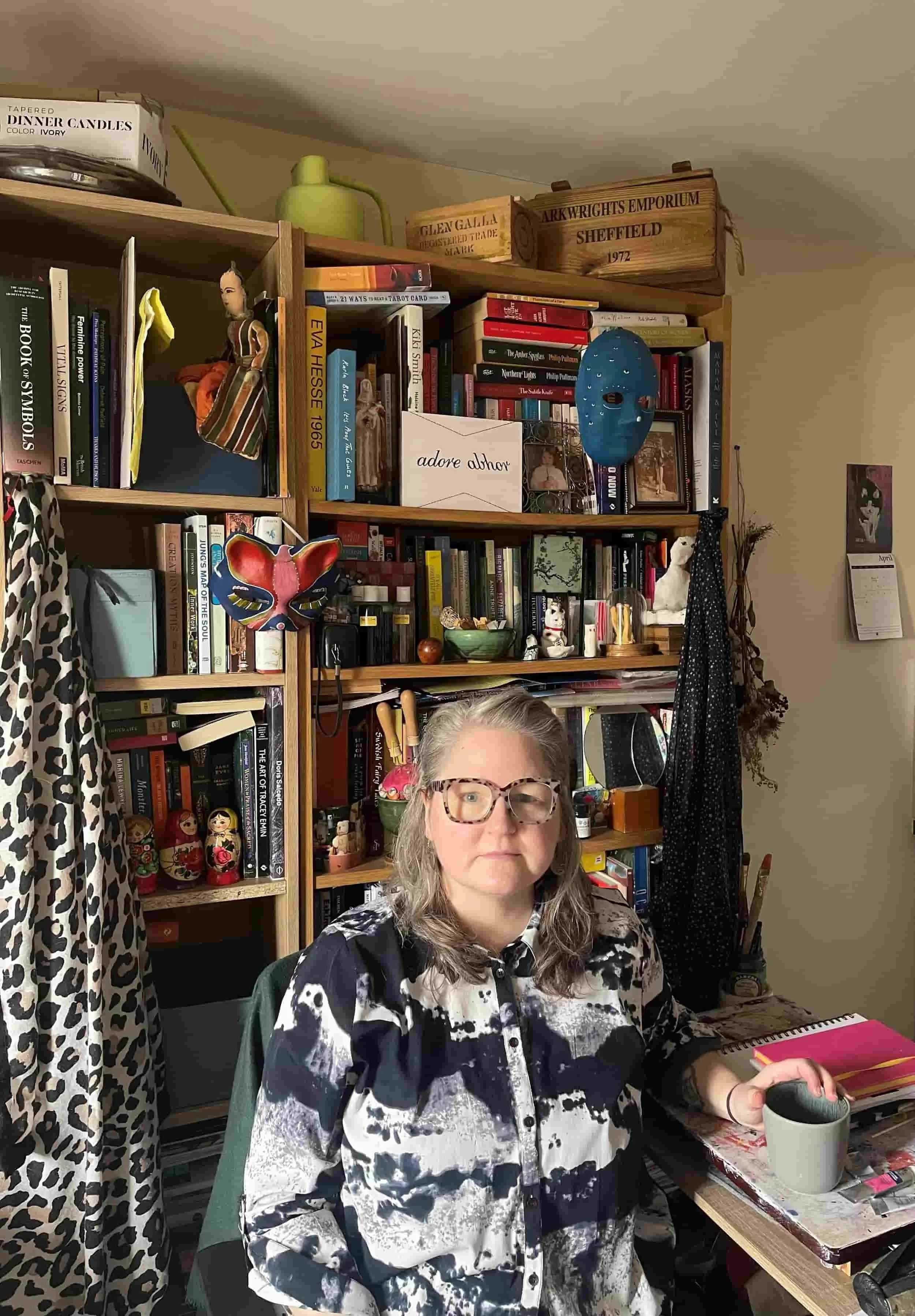 Sara sitting in front of packed bookshelves containing meaningful objects