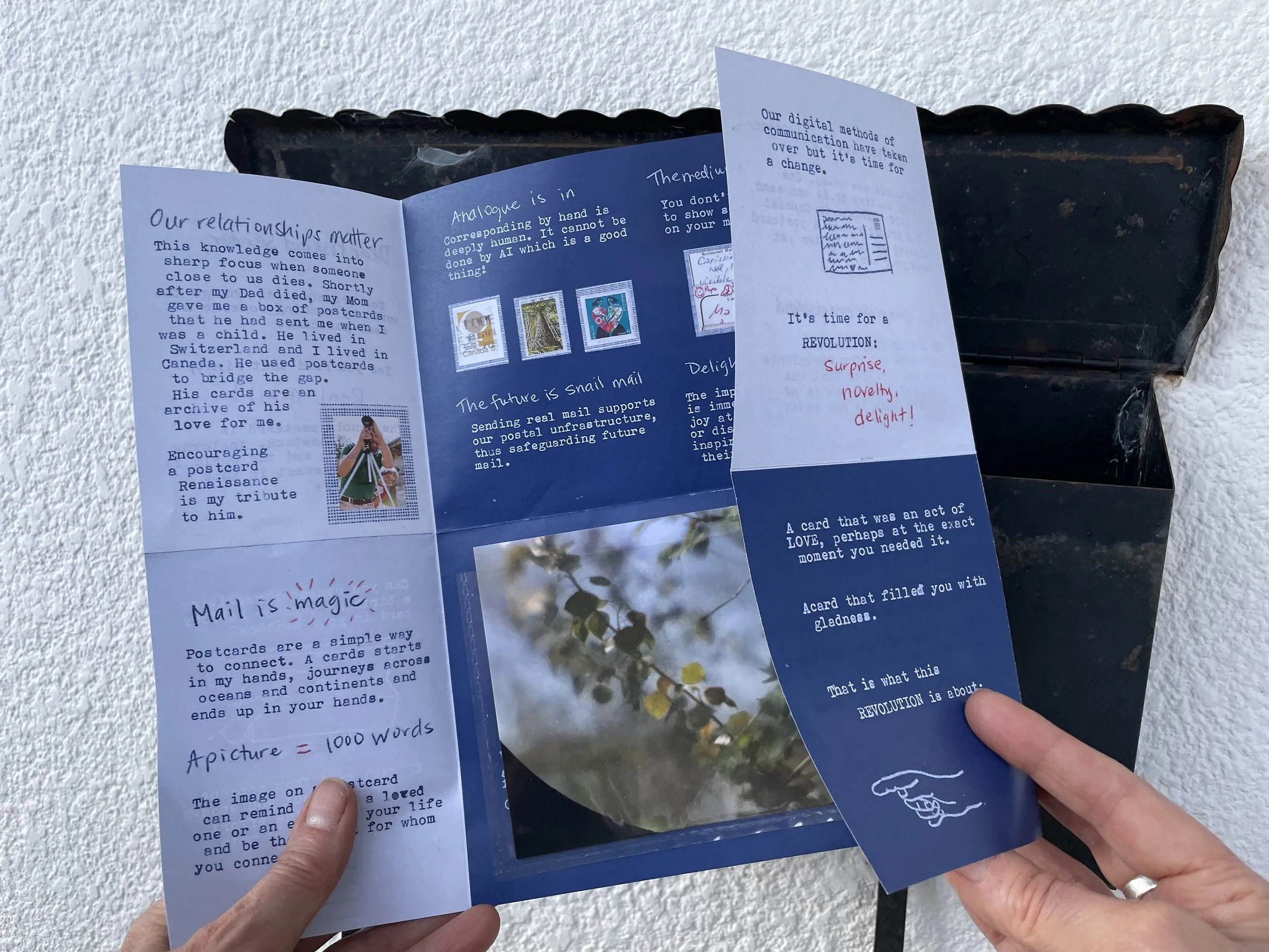 Fully unfolded 'One Postcard at a Time: a MANIFESTO! revealing a pocket with another postcard.