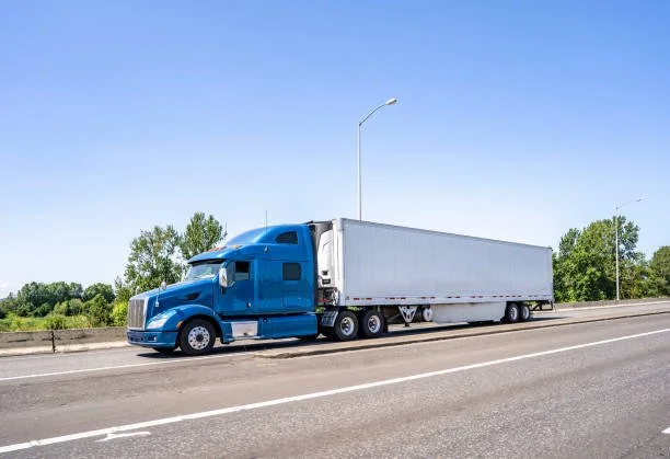 Blue semi-truck with white trailer on highway