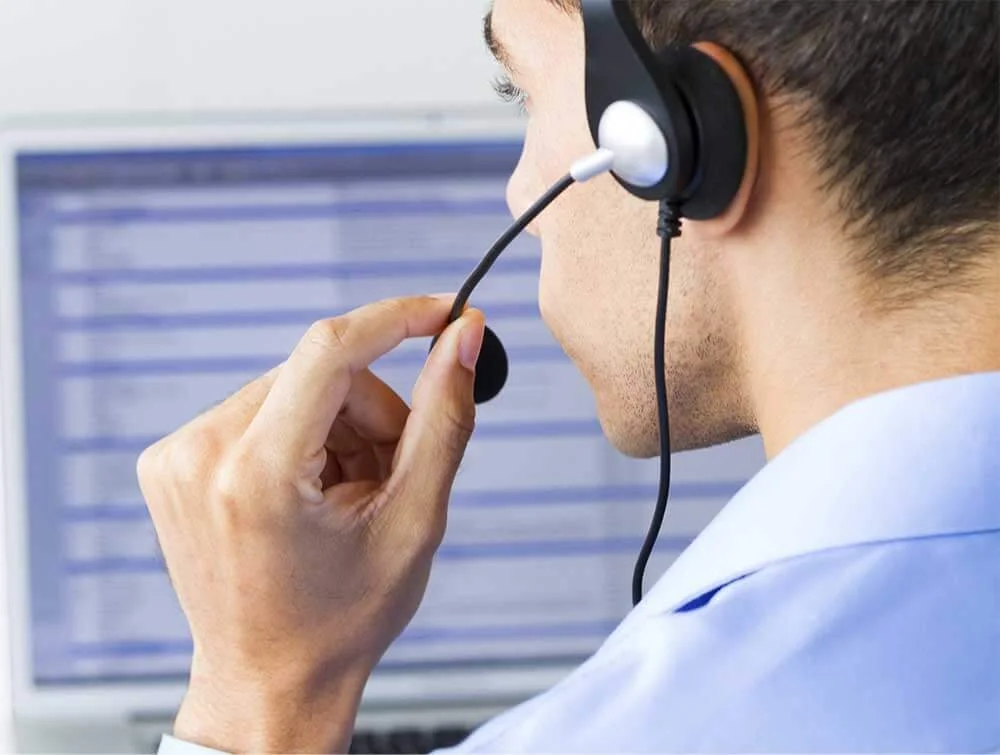 Person wearing a headset while looking at a computer screen, possibly working in customer service or call center.