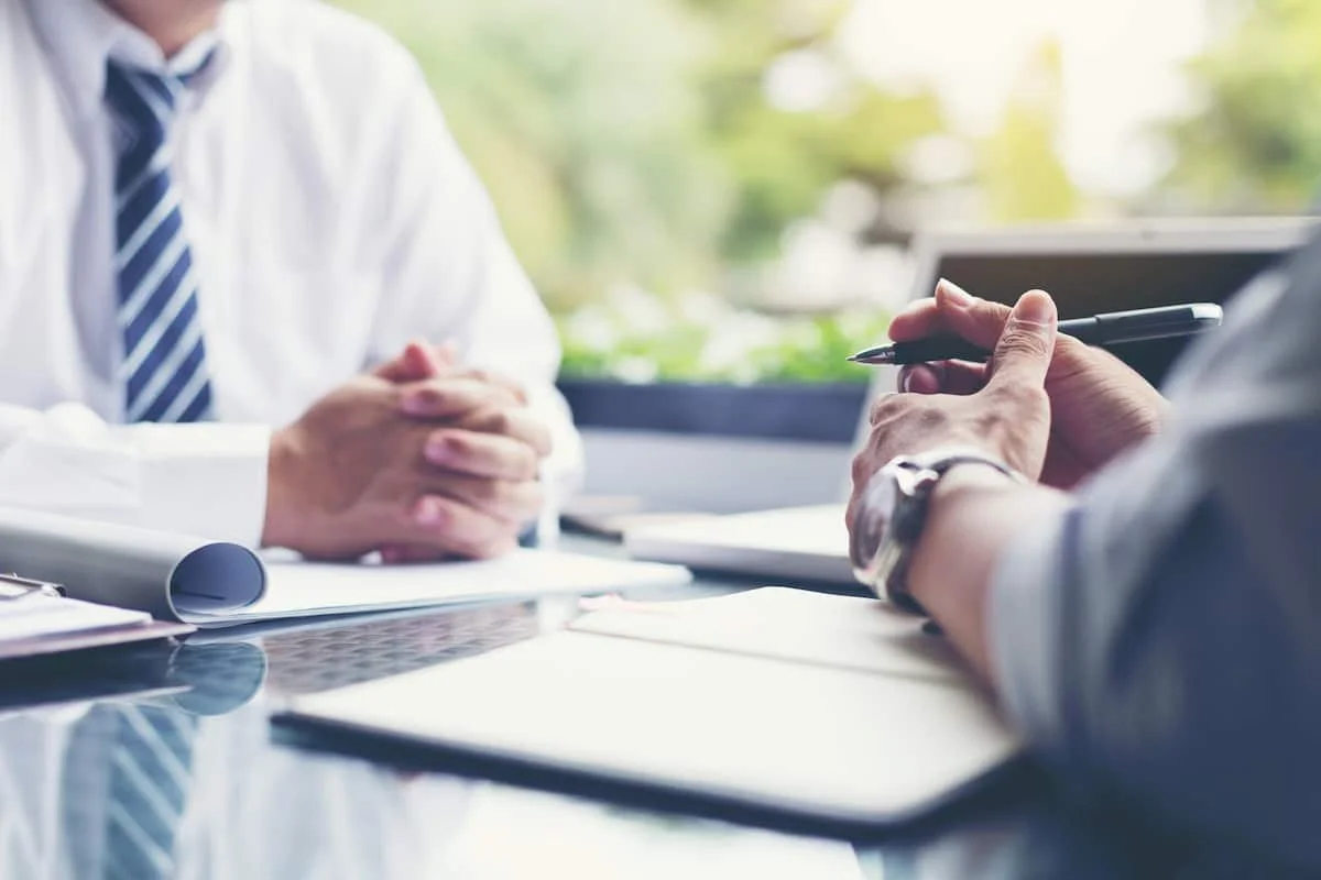 Two people having a business meeting at a desk with documents and laptop.