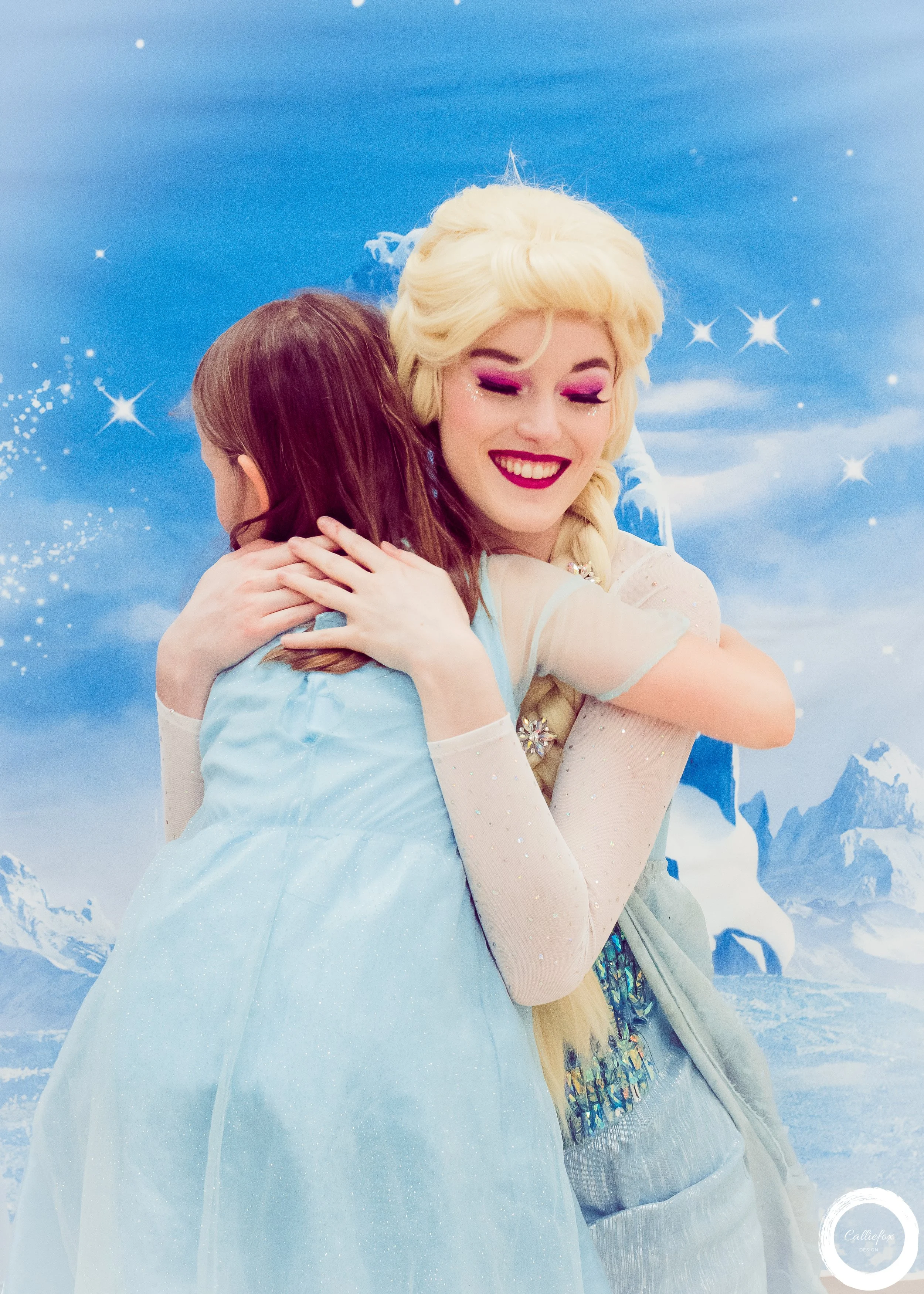Two princesses hugging, one dressed as the Ice Queen, and the other a young girl with brown hair, in front of a blue sky background with clouds, snow, and icy mountains.