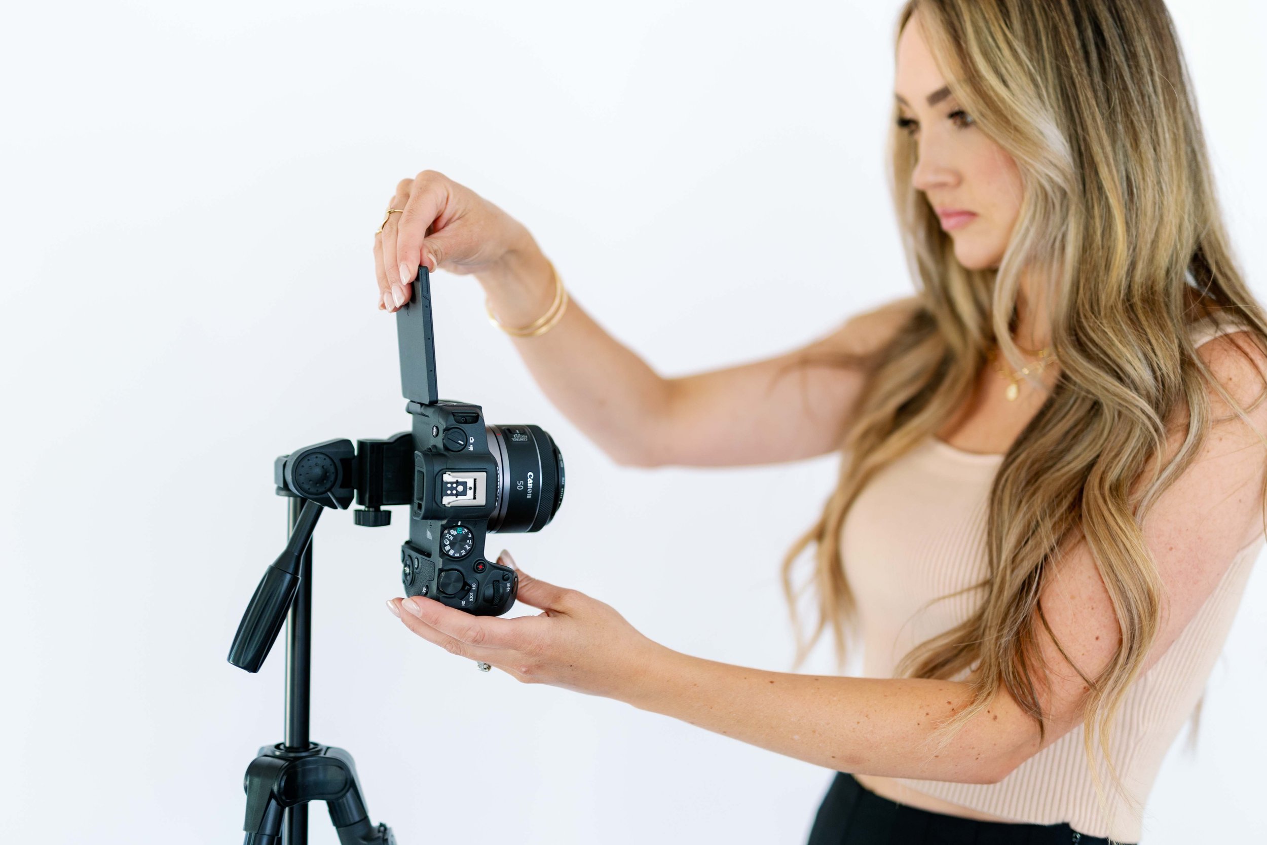 Brand photographer preparing camera on tripod during personal branding session in Medford Oregon studio.