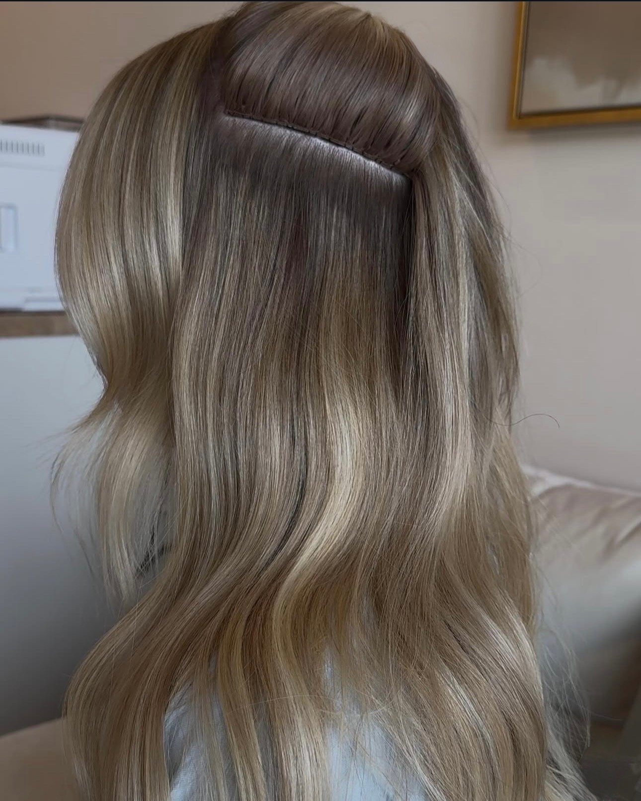 Close-up of long, wavy blonde hair showing an invisible wig or hair extension on a mannequin head.