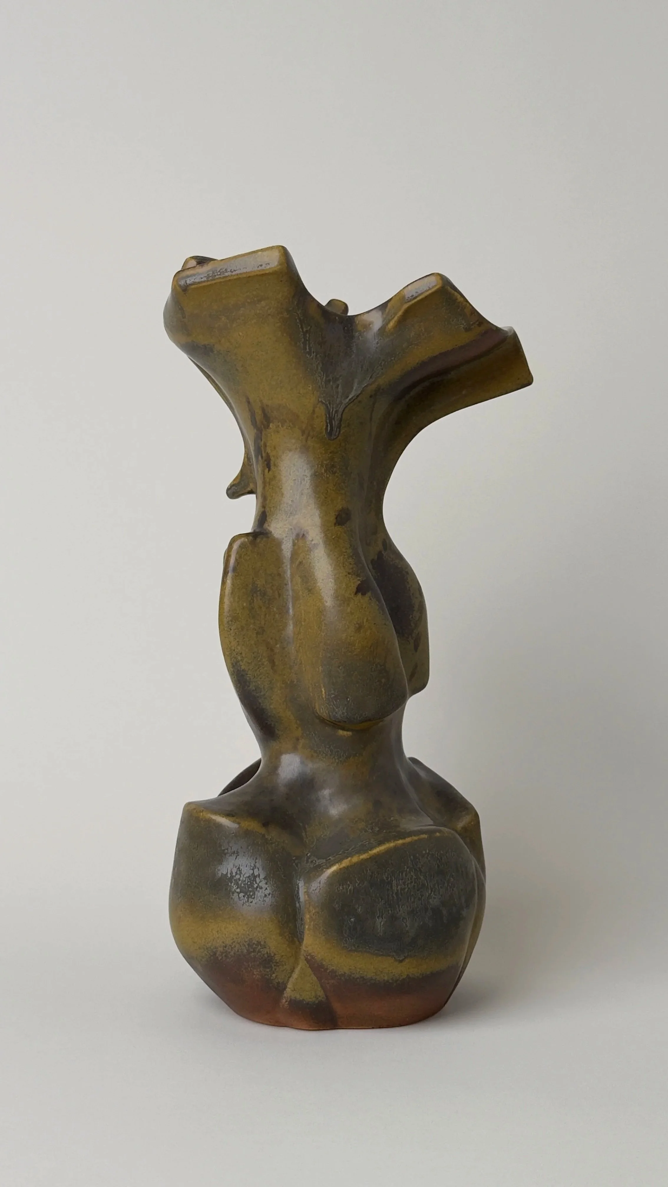 Sculptural ceramic vessel with an elongated organic form, branching openings and a dark bronze and black glazed surface.