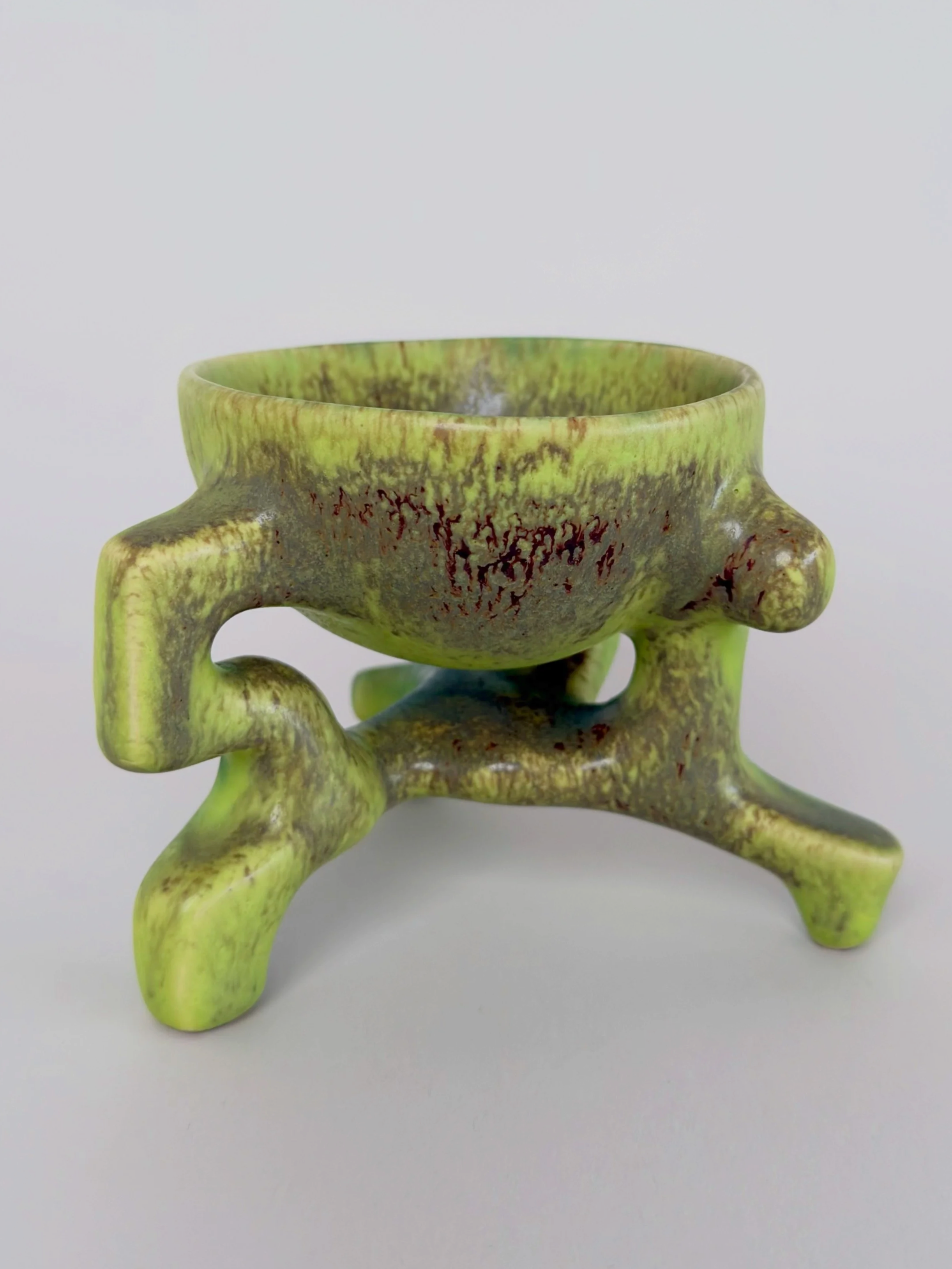 Poisonous Frog Cup, sculptural ceramic cup with a green and yellow glaze and an organic four-legged base.