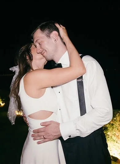 A couple kissing at night, dressed in formal attire, celebrating a special occasion.