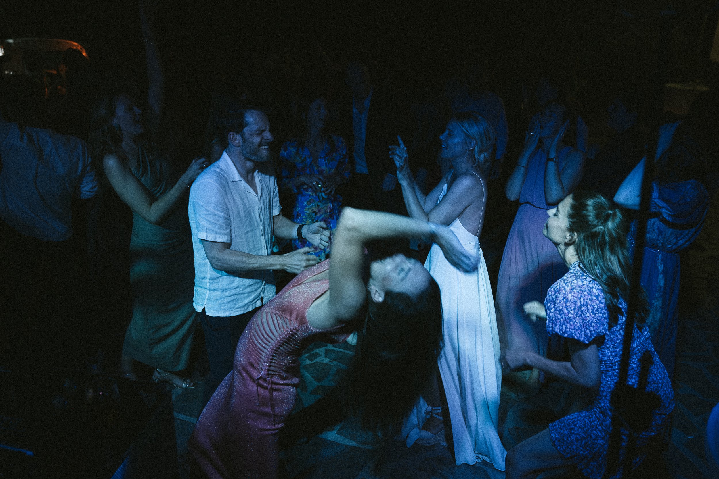 People dancing and enjoying themselves at a party under blue lighting.