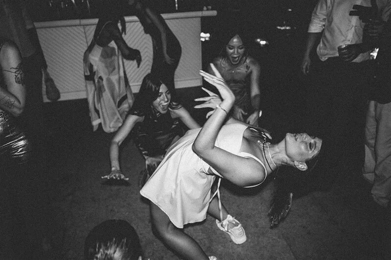 A group of women dancing and having fun at a party with dark lighting.