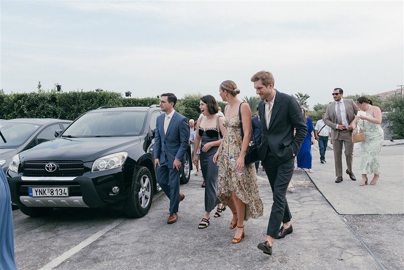 Group of people in formal attire walking in a parking lot.