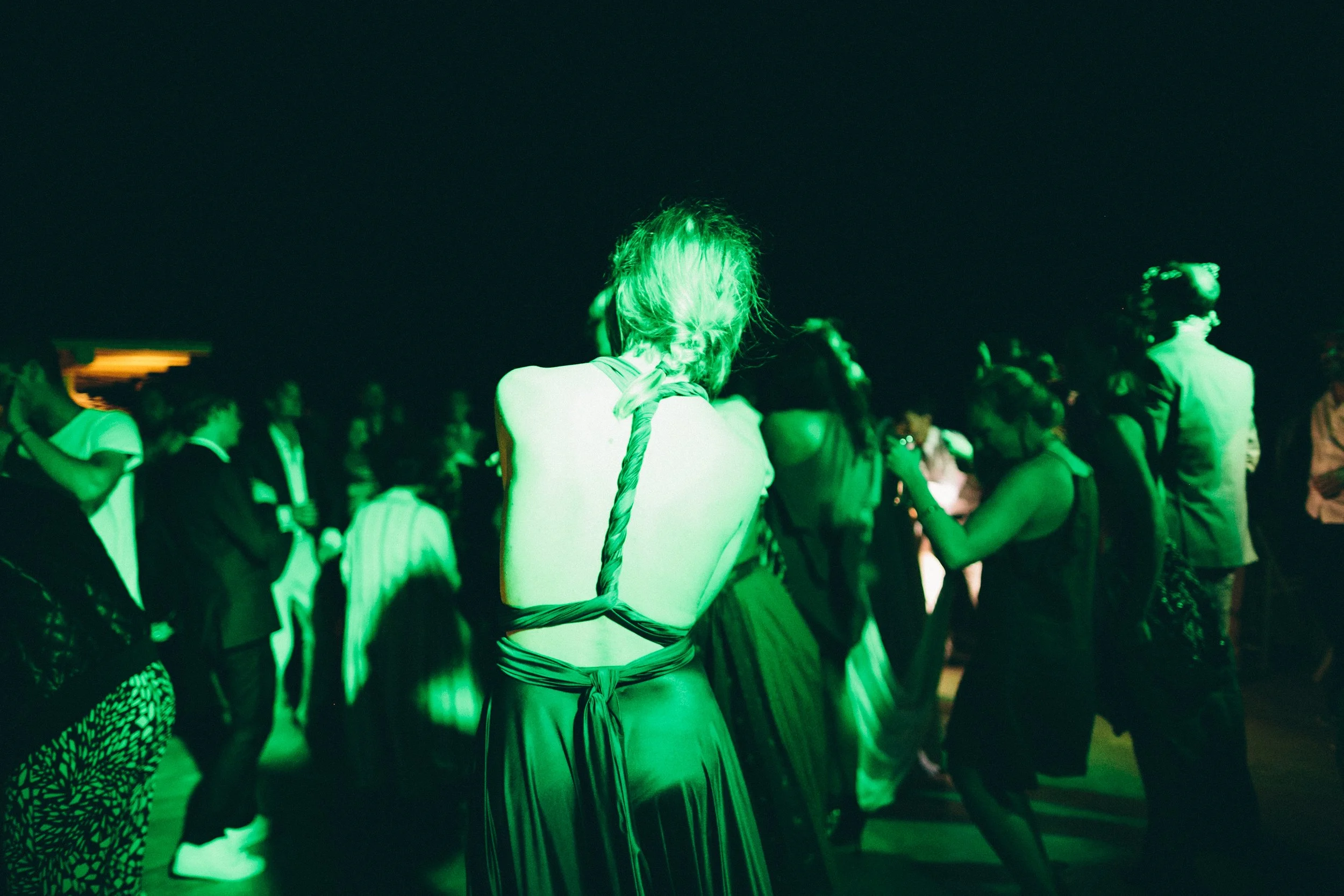 People dancing at a party or event with green lighting.