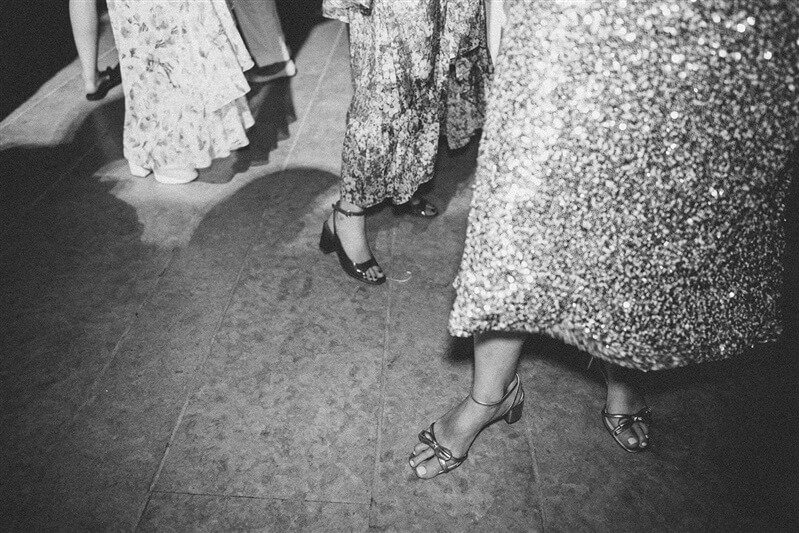 A group of women wearing high heels and long dresses standing on a floor.