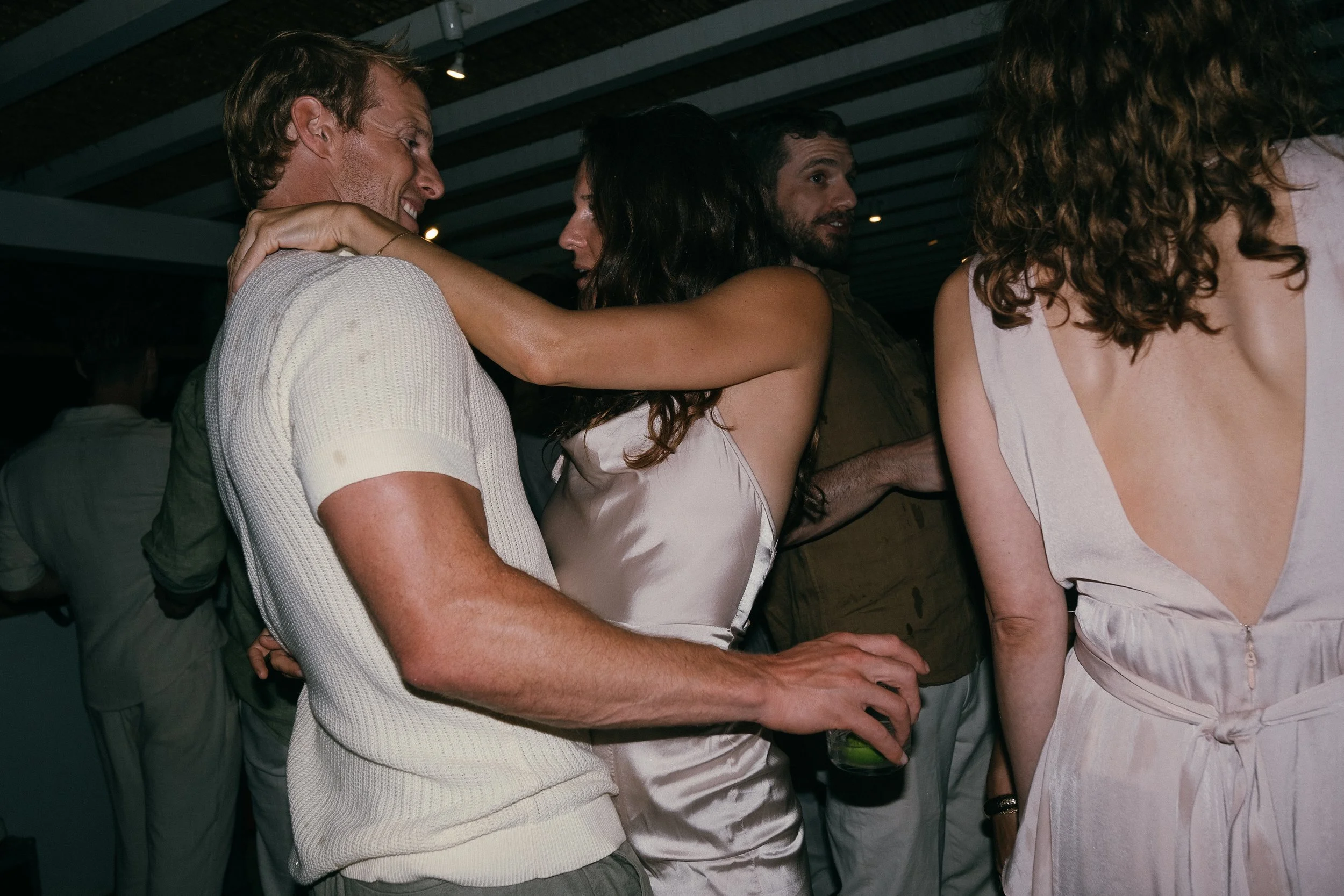Group of people at a party, engaging in conversation and dancing.