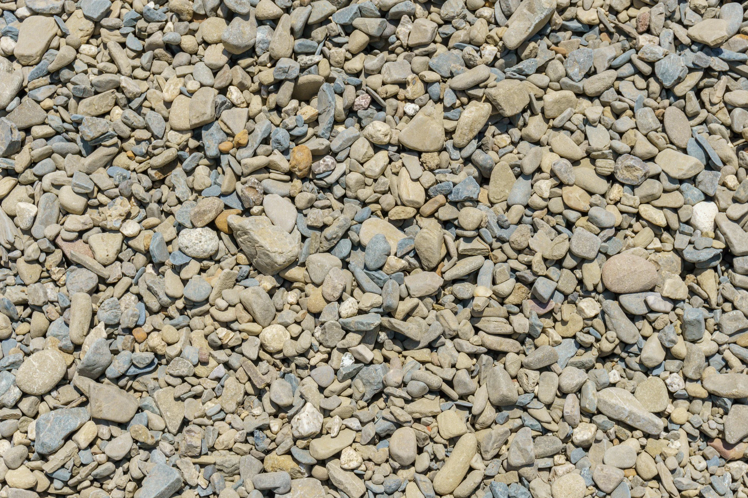 A close-up view of a ground surface covered with small, irregularly shaped pebbles and stones of various sizes and colors.