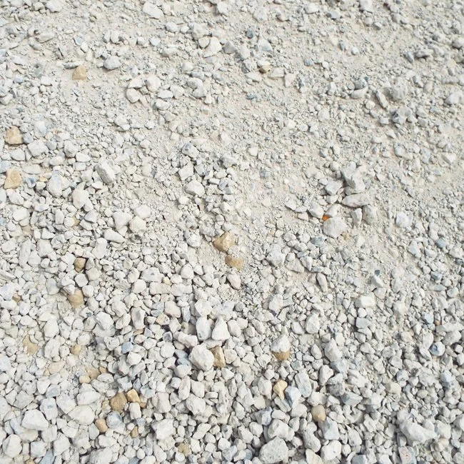Close-up of small, beige and gray gravel stones on the ground.