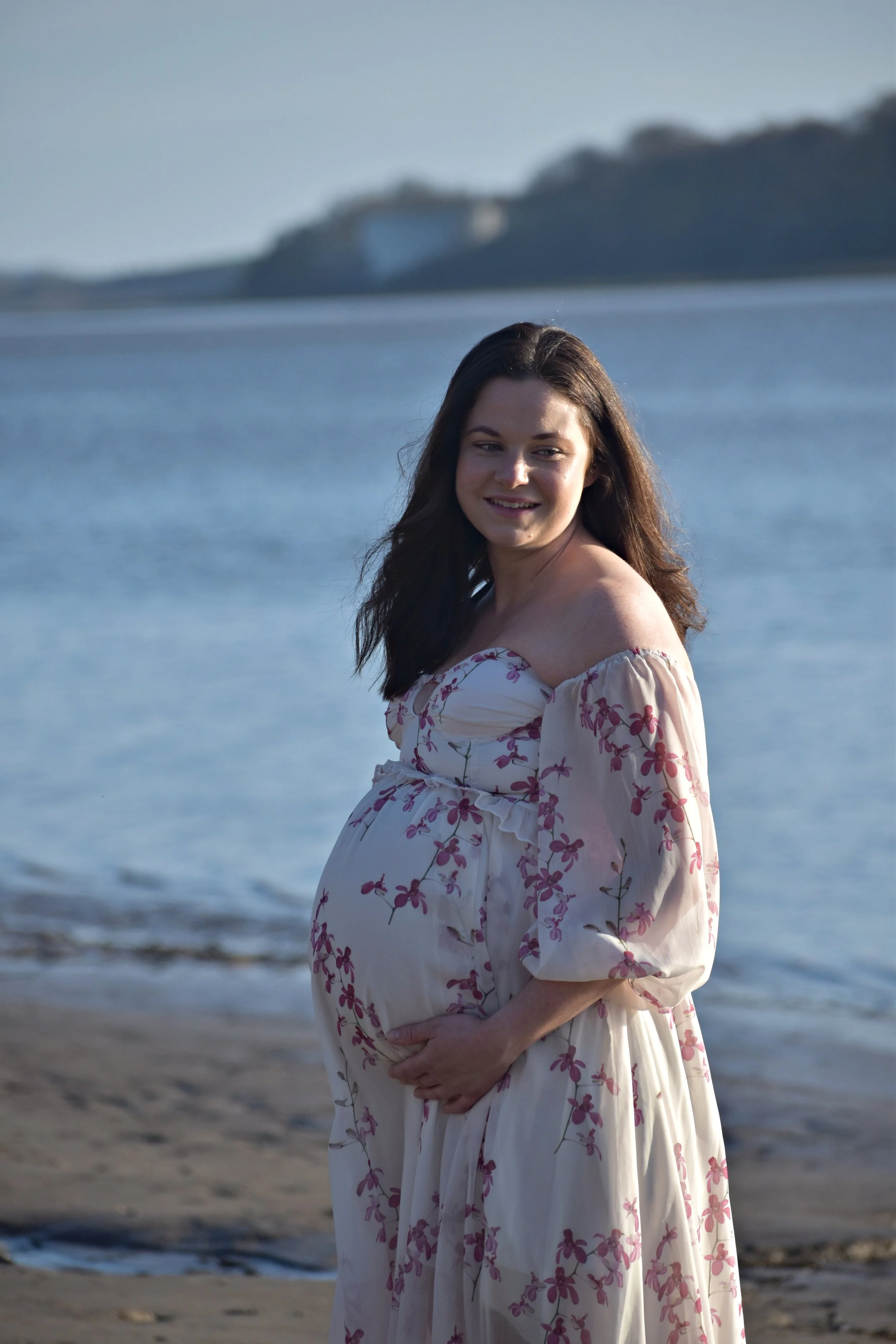 Pregnant woman in floral dress by the beach