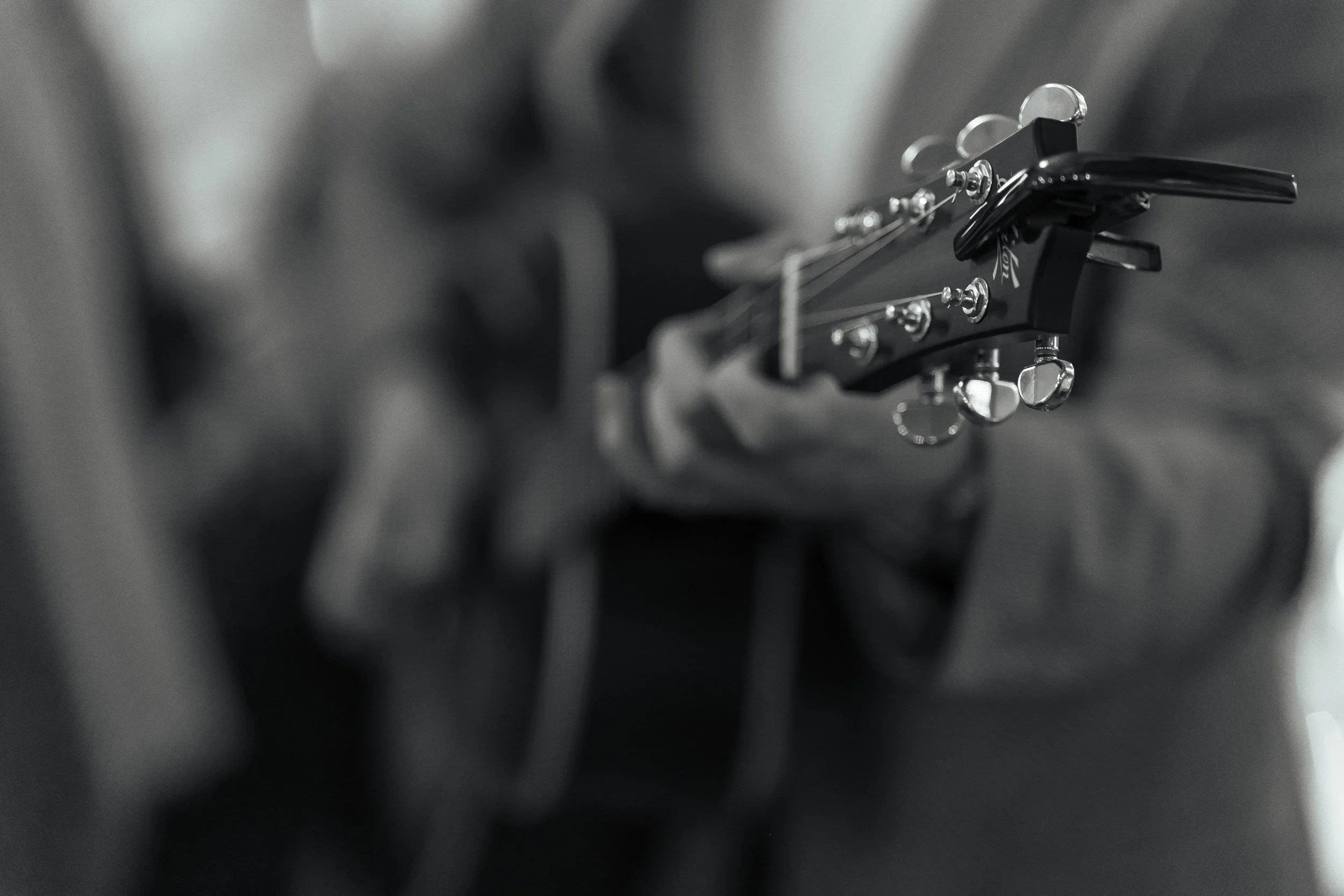 Close-up of a guitar's headstock with tuning pegs and strings, black and white photo.