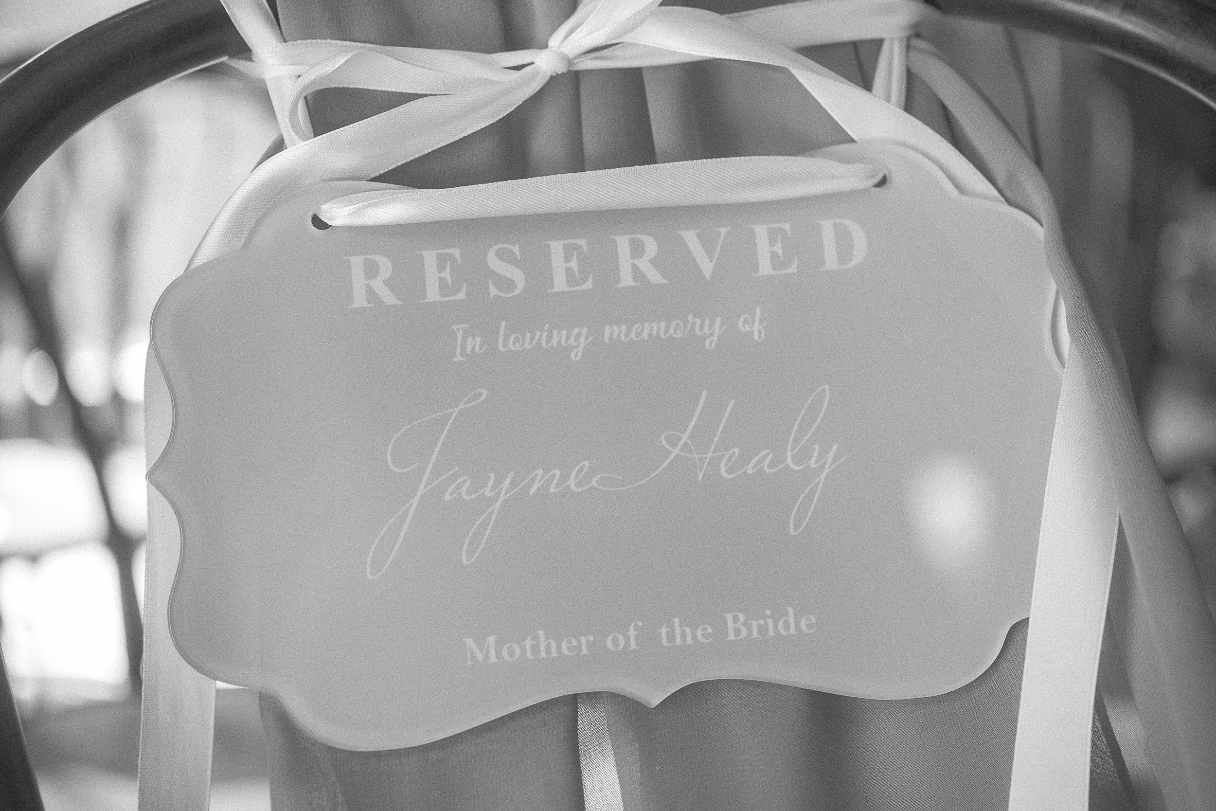 Close-up of a reserved sign attached to a gift bag, with ribbons and a blurred background.