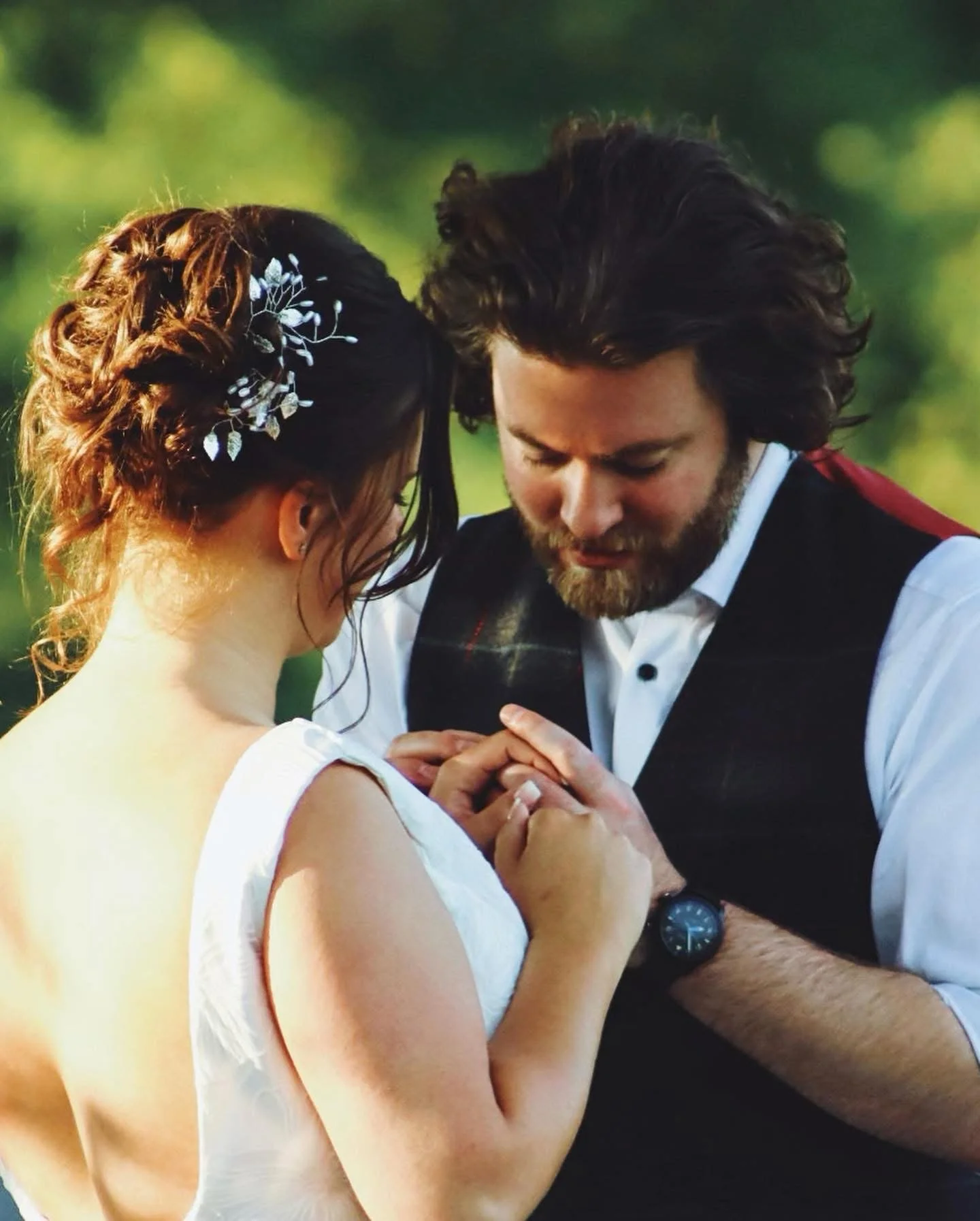 Bride and groom holding hands during wedding ceremony outdoors.