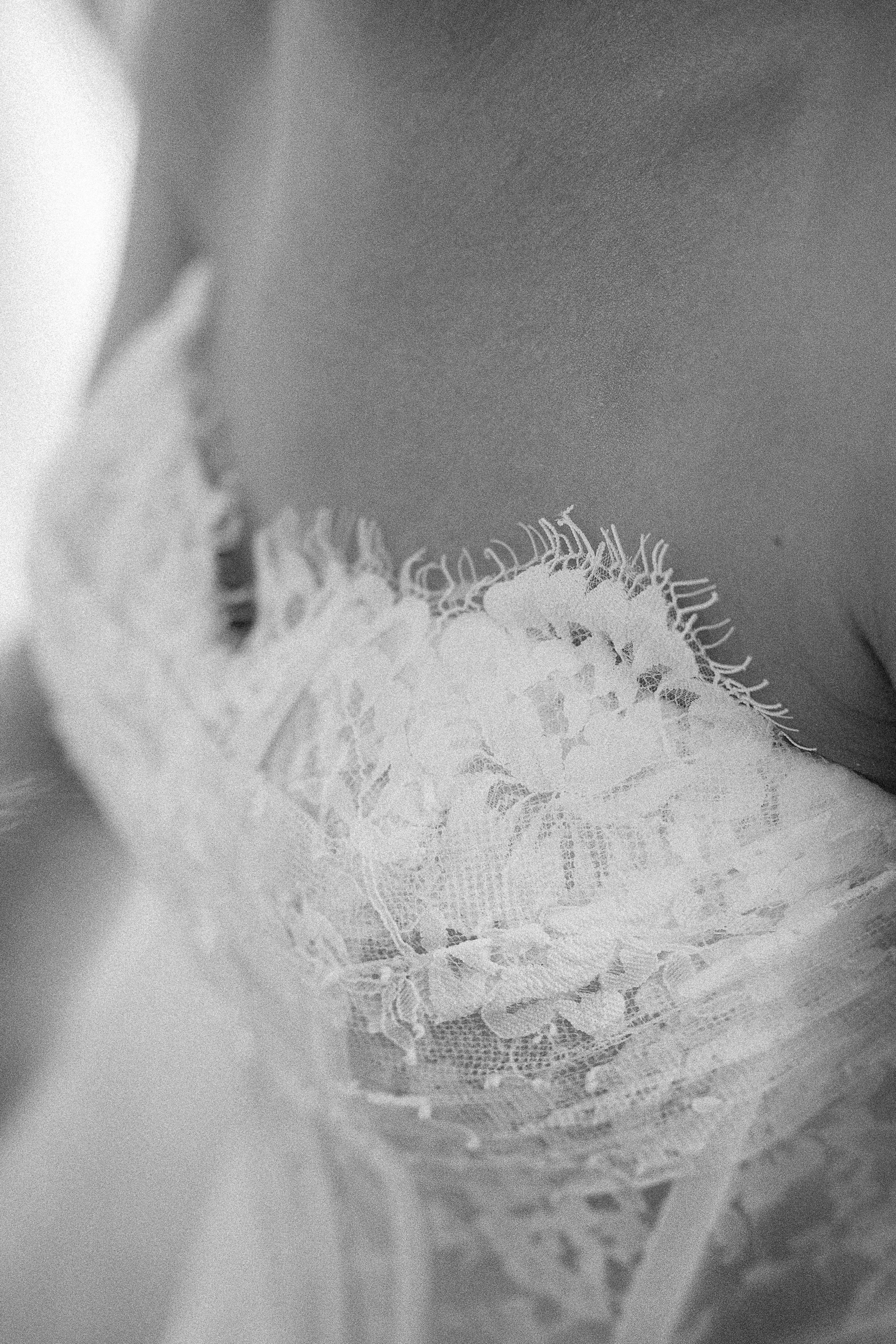 Close-up of lace fabric with intricate floral patterns, in grayscale.