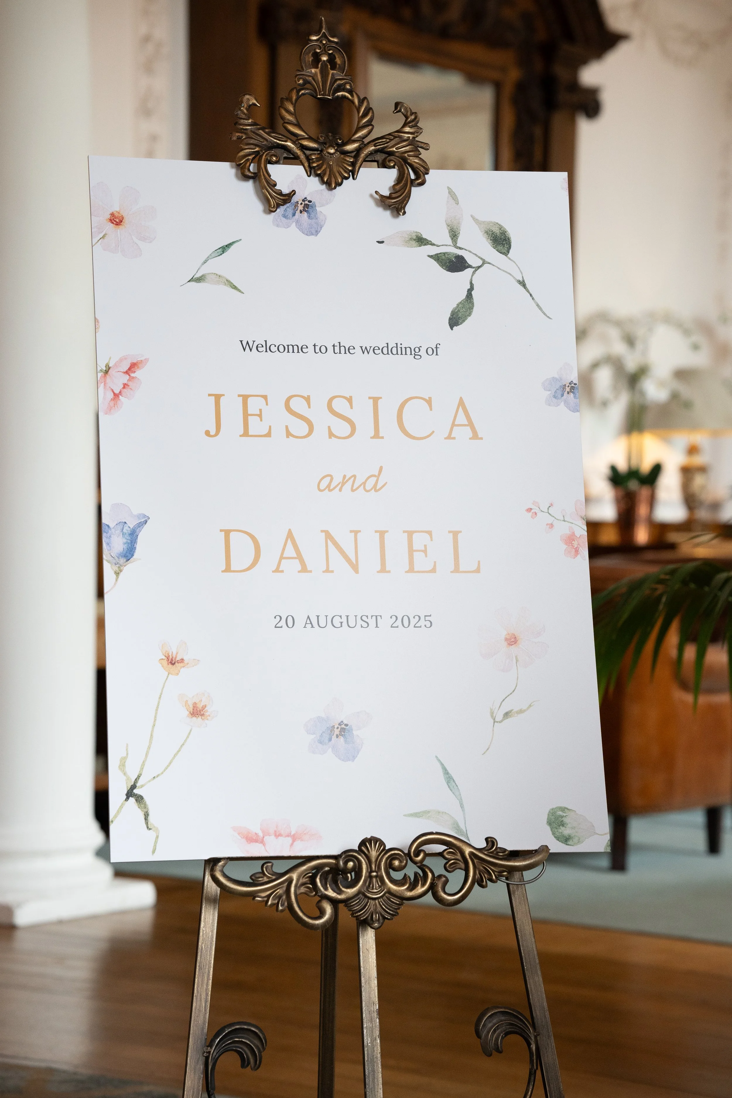 Wedding welcome sign for Jessica and Daniel on August 20, 2025, decorated with watercolor flowers on a stand.