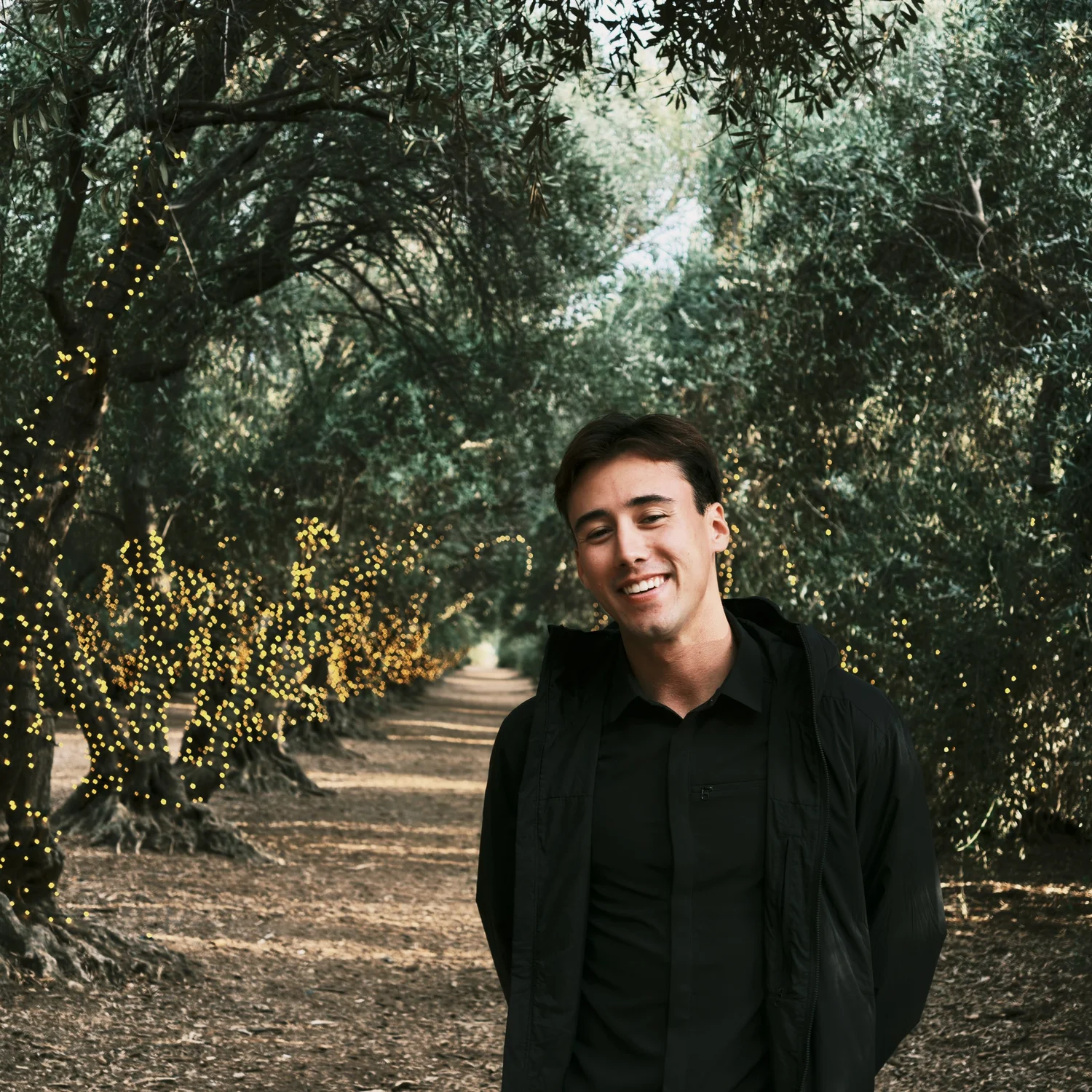 Isaak Rowe smiling beneath trees and string lights