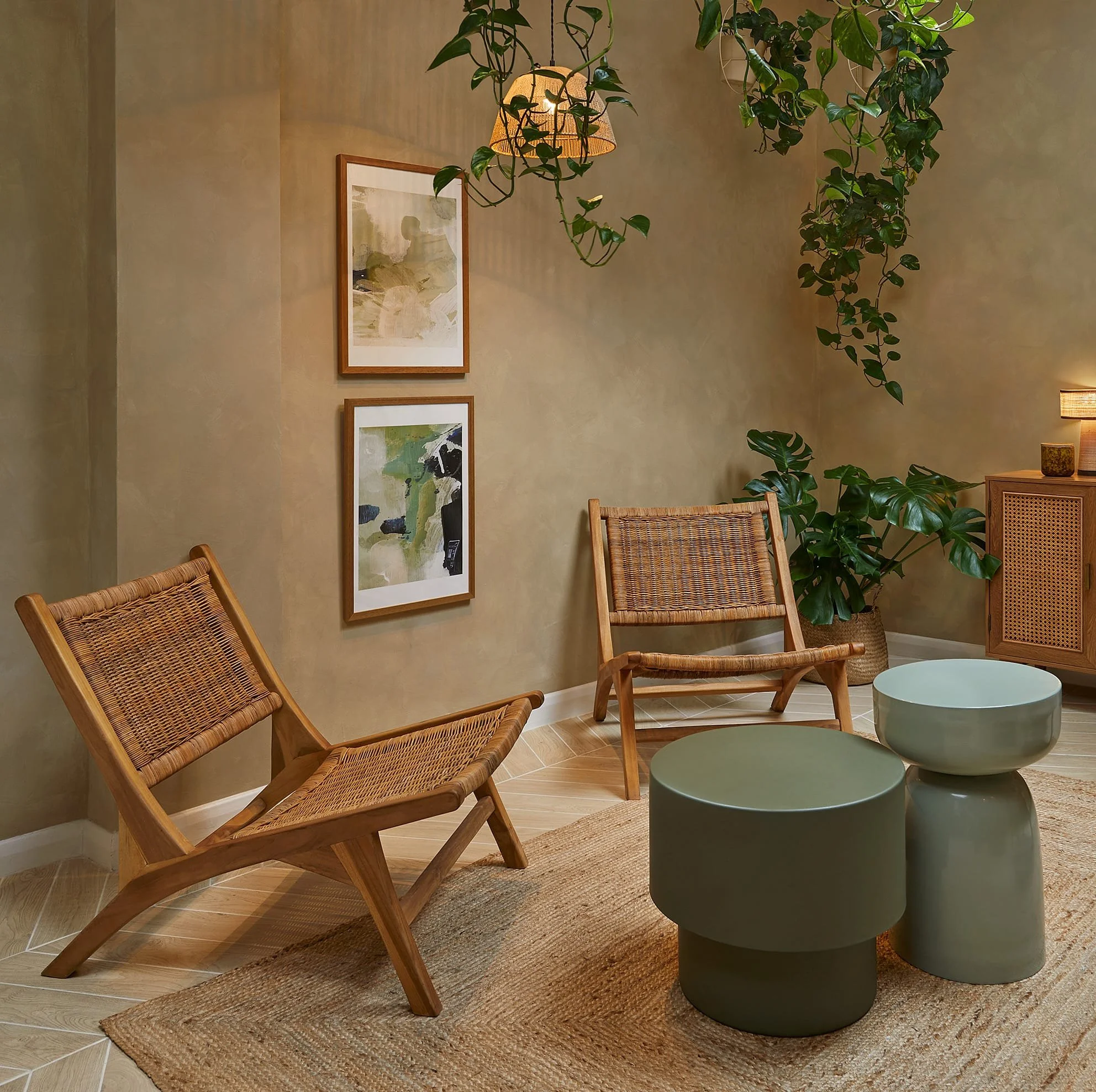 Living room with two wooden chairs, two green and beige side tables, a potted plant, artwork on the wall, and a hanging lamp.