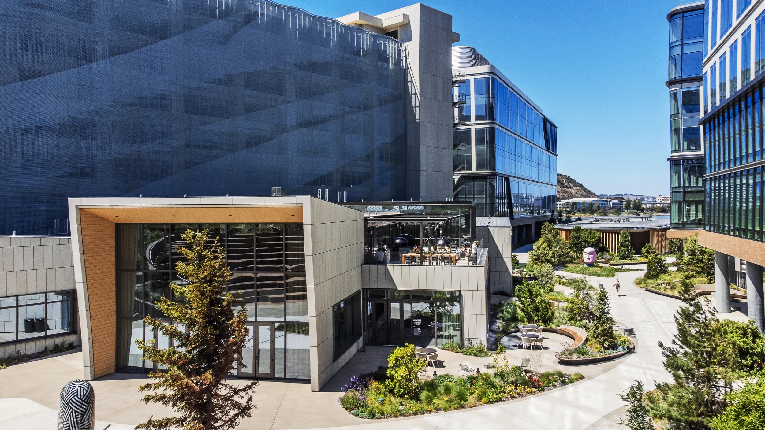 Exterior of Farewinds' waterfront rooftop terrace with bay views, surrounded by a landscaped courtyard with trees and walkways.