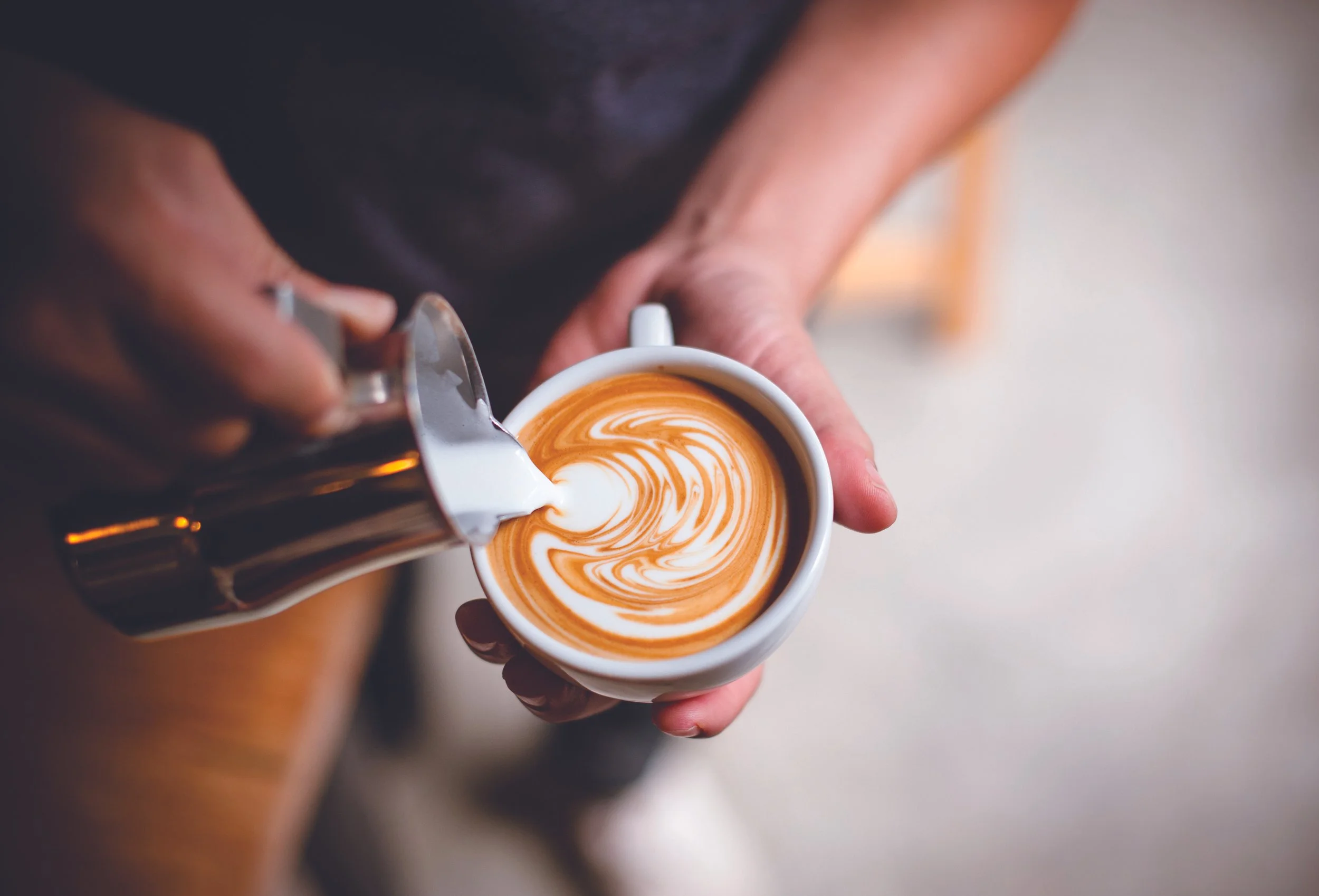  Barista pouring steamed milk into an latte. 