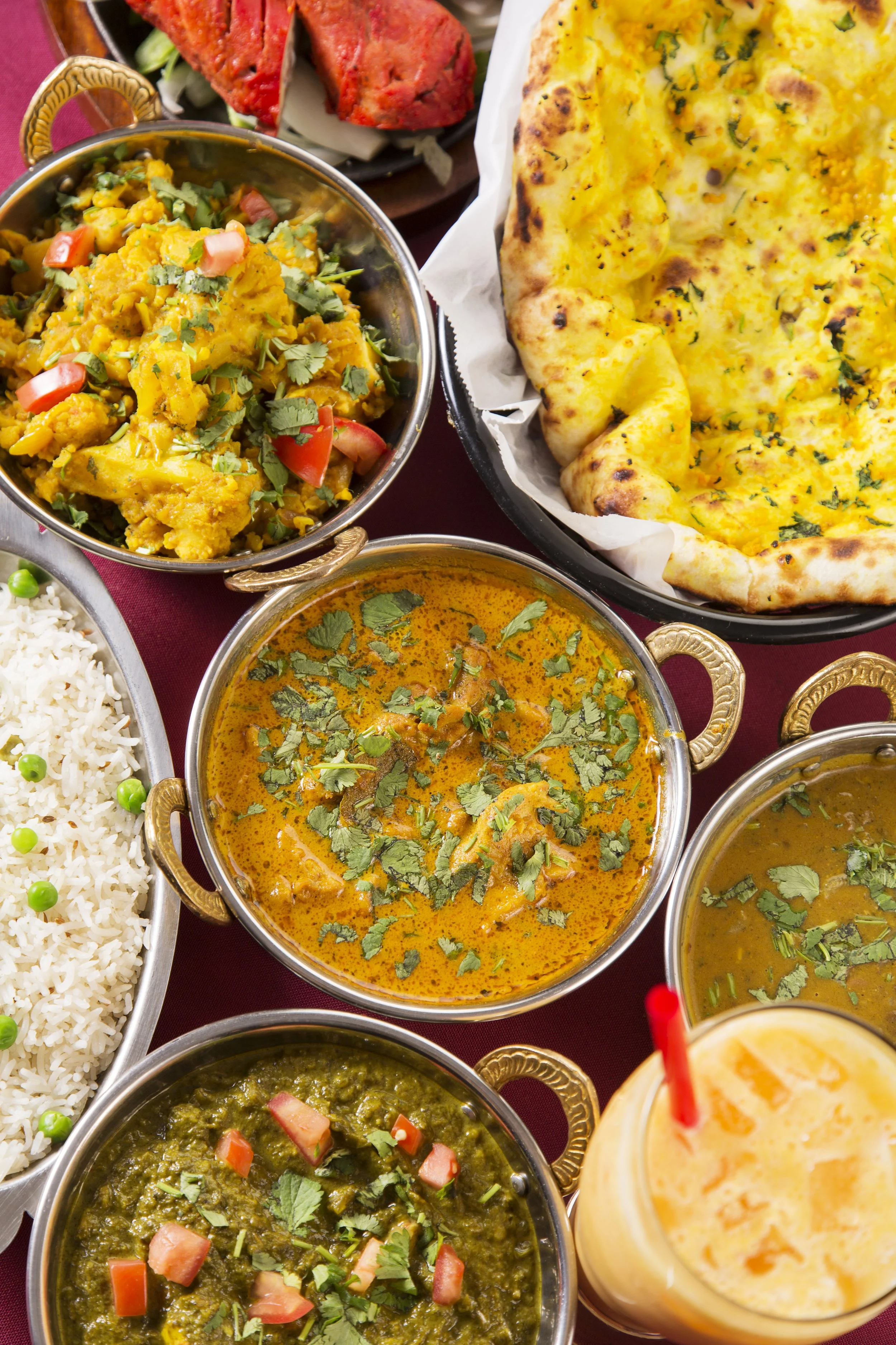  Top view of a selection of Indian curries with rice and naan bread, all in small metal bowls 