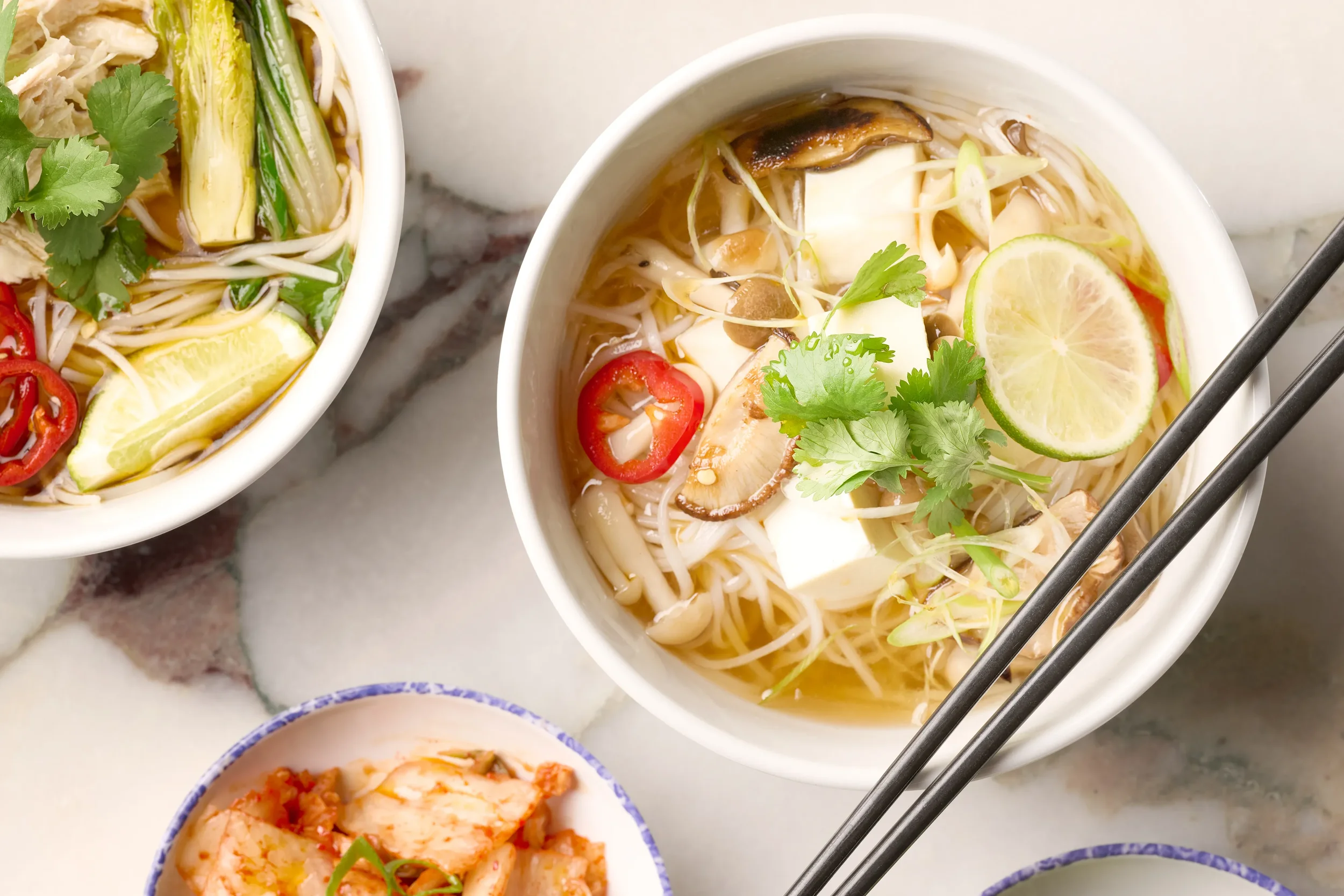 Overhead view of two bowls of pho and a small bowl of kimchi from Noodle Bar in Farewinds Food Hall.