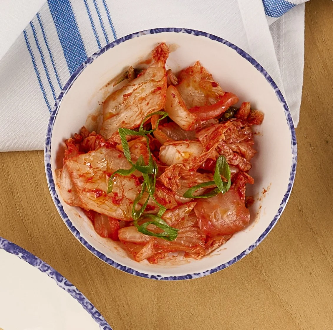 Overhead view of a white bowl with house made vegan kimchi  from the Noodle Bar slip in Farewinds Market Hall.