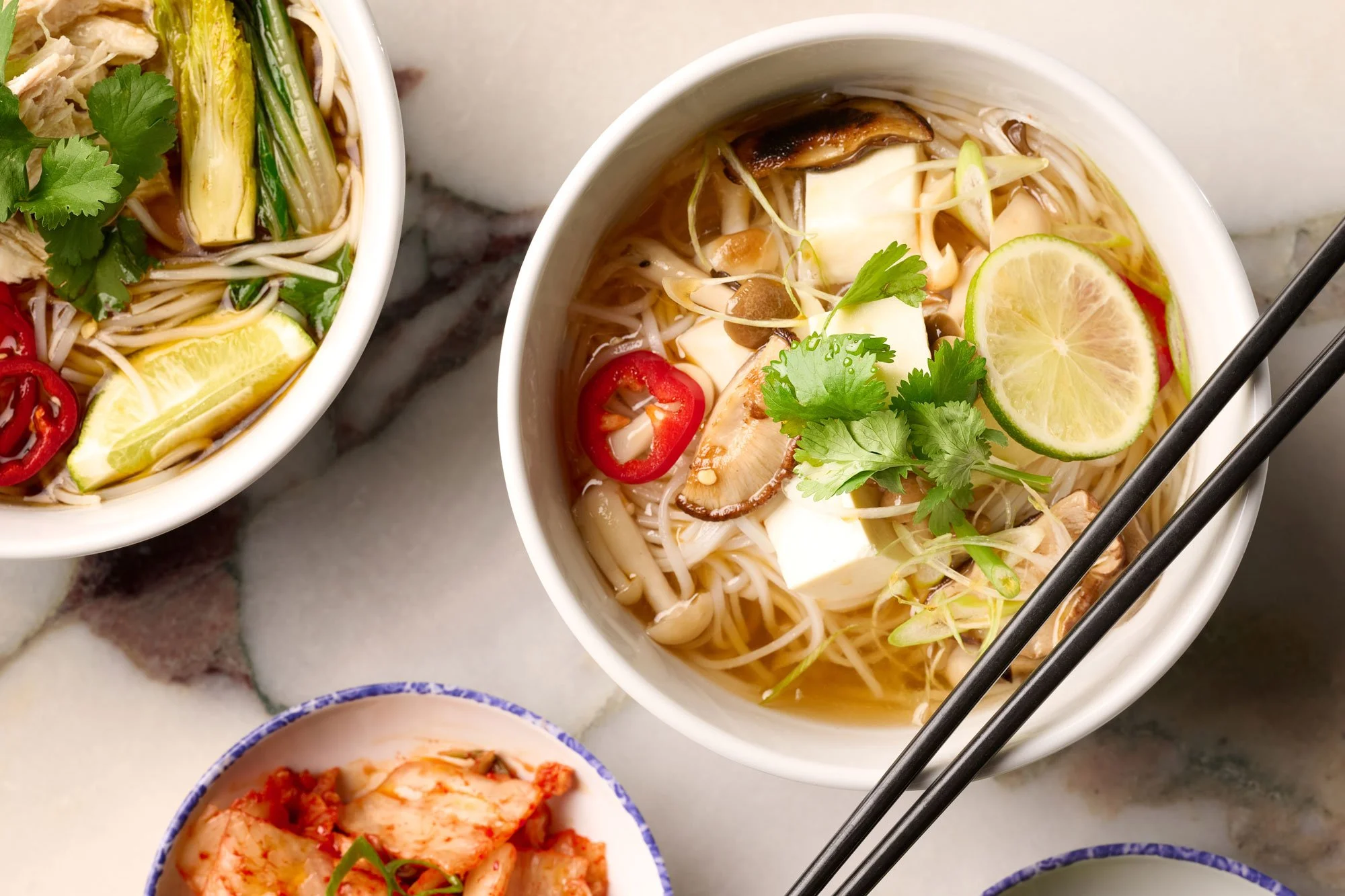 Overhead view of two bowls of pho and a small bowl of kimchi from the Noodle Bar slip in Farewinds Market Hall