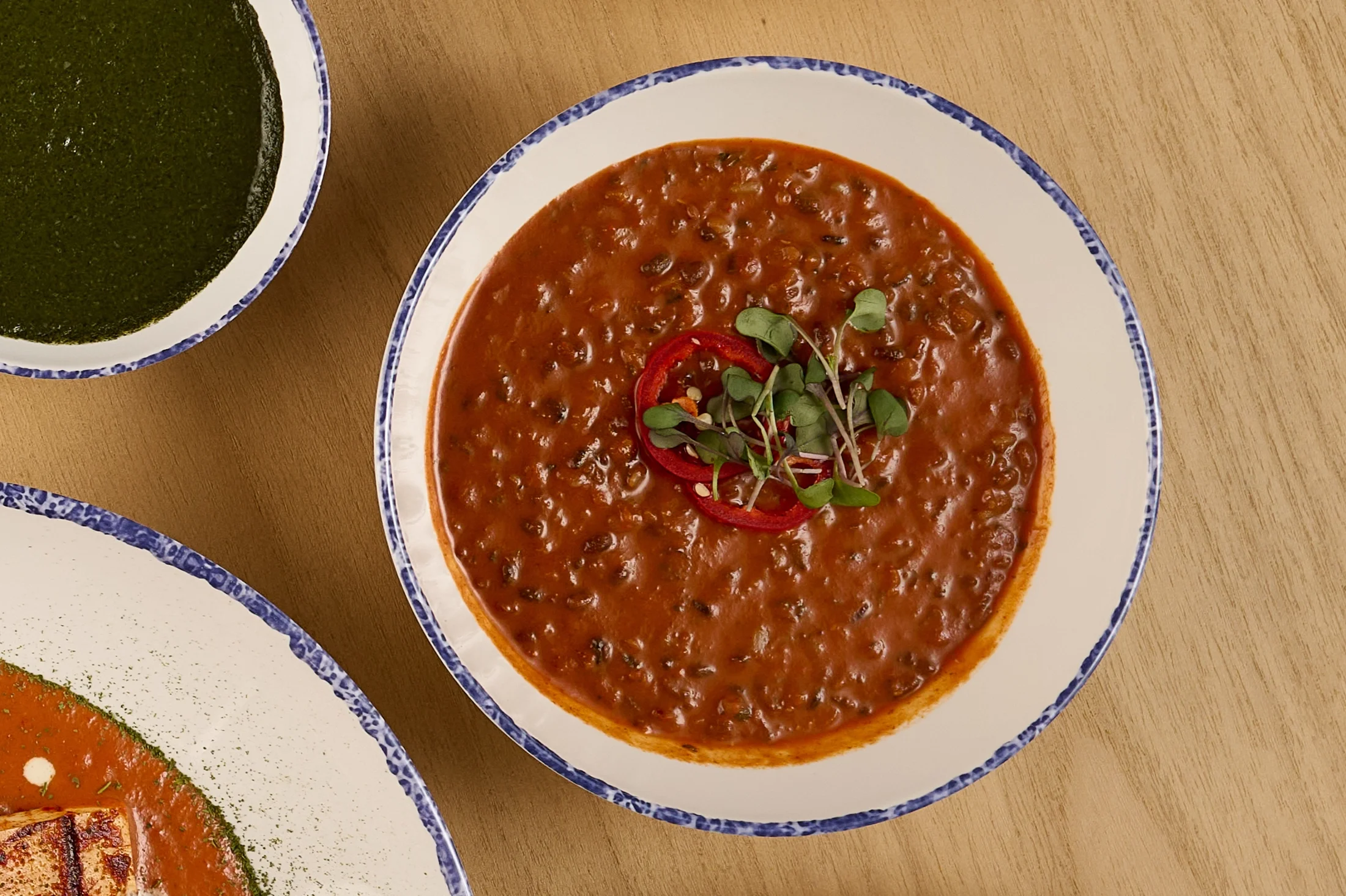 Overhead view of a white bowl with braised black urad, butter lentils, and kidney beans from the Samudra in Farewinds Food Hall.