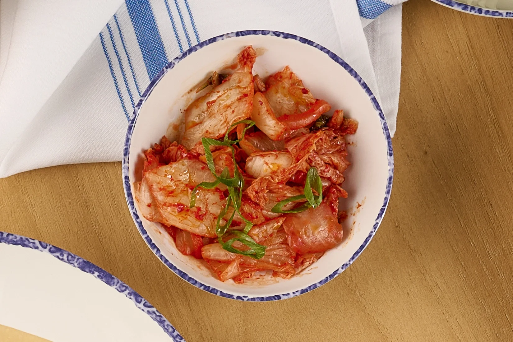 Overhead view of a white bowl with house made vegan kimchi  from the Noodle Bar slip in Farewinds Food Hall.