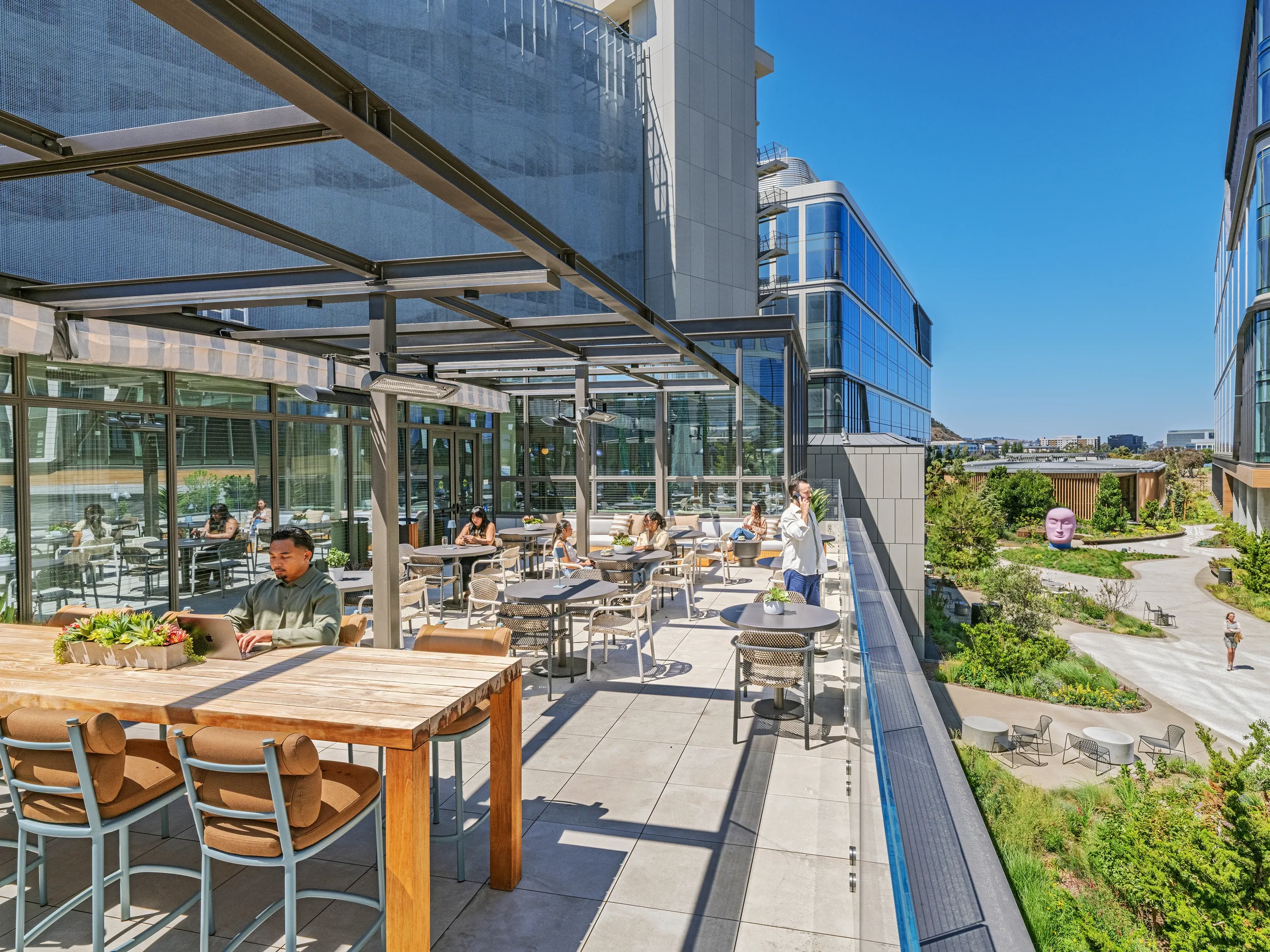 Customers sitting on the reservable open-air rooftop terrace at Farewinds with a variety of tables and a views landscaped pathway.
