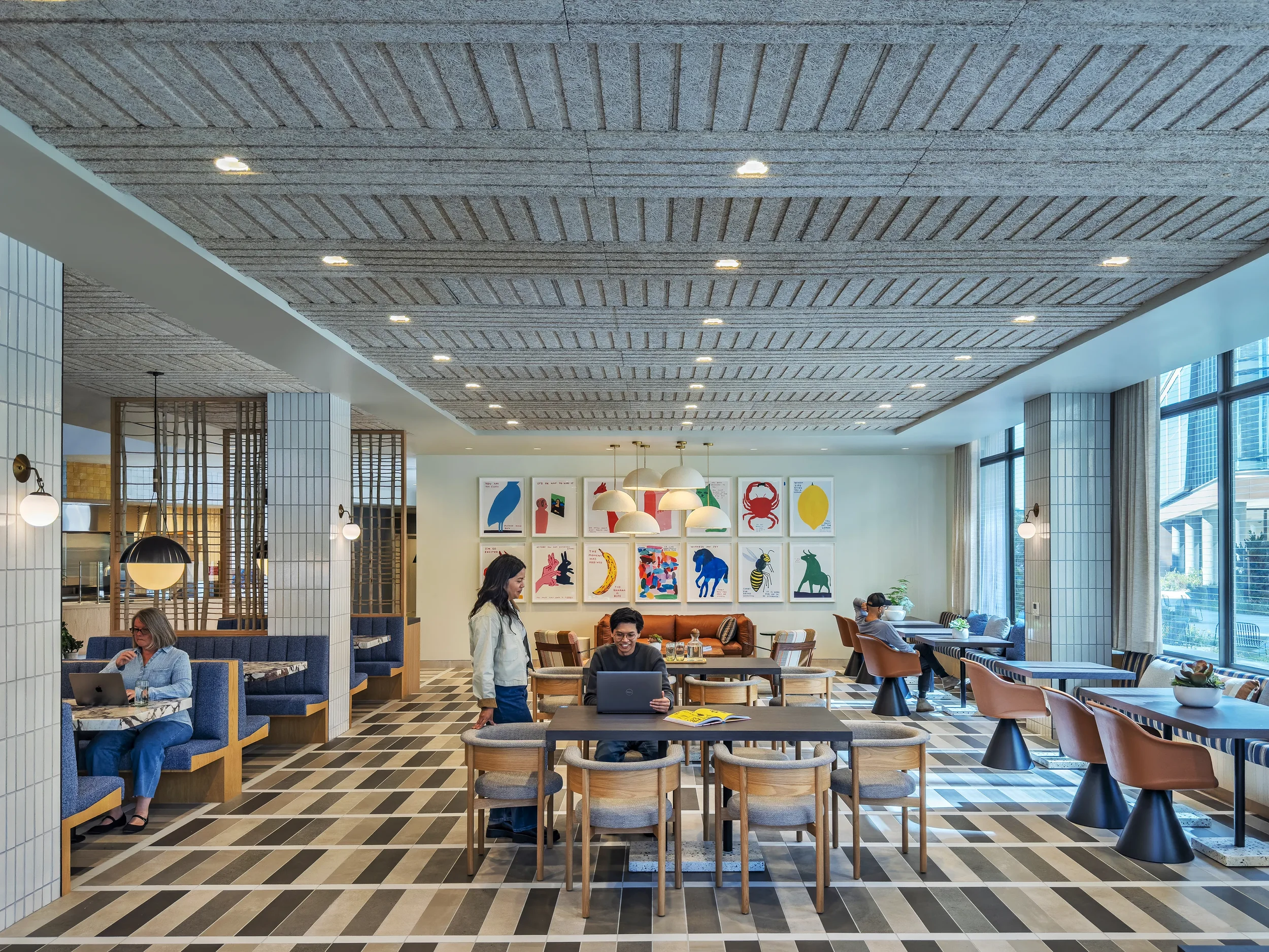 A few customers sitting in a reservable vibrant open dining room at Farewinds with a mix of tables and booths, colorful artwork on the wall, and large windows.
