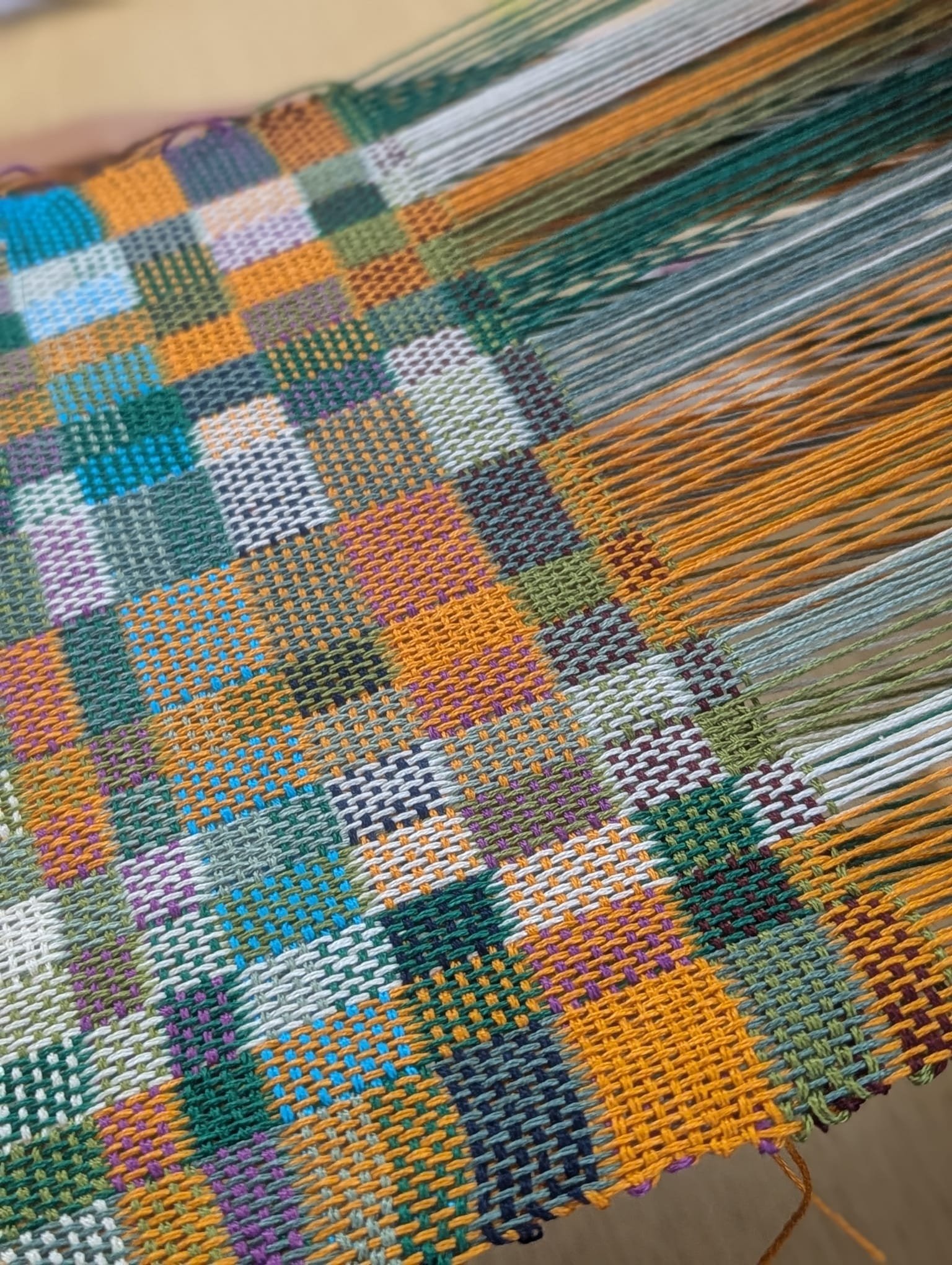 Close-up of colorful woven fabric with a checkered pattern in various colors including purple, blue, orange, green, and white.