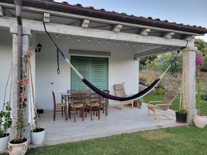 Outdoor patio with a hammock, dining table, chairs, potted plants, and garden view