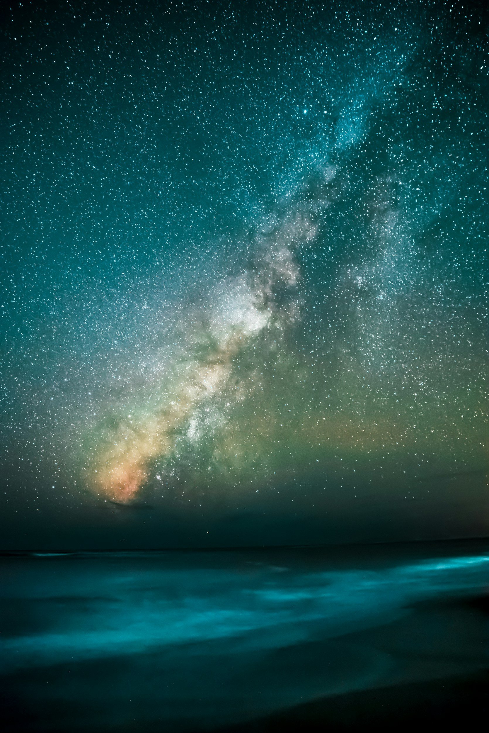 A starry night sky with the Milky Way galaxy visible over a calm ocean.
