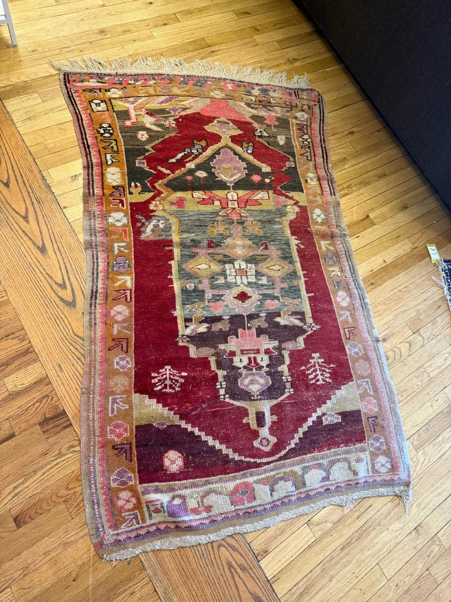 A colorful, patterned area rug with red, pink, beige, gray, and black geometric designs 