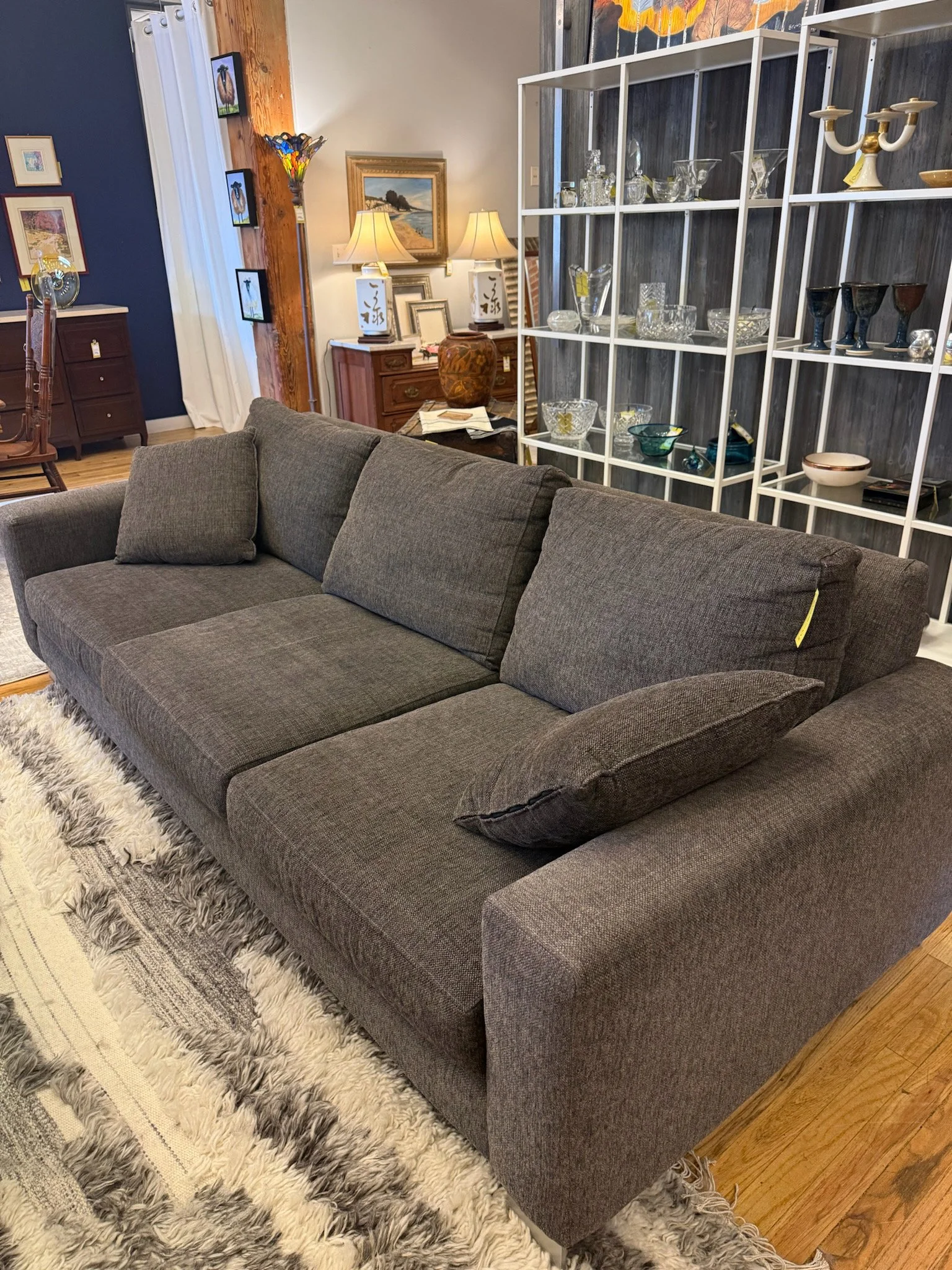 Grey upholstered three seater sofa with sleek metal legs and matching accent pillows