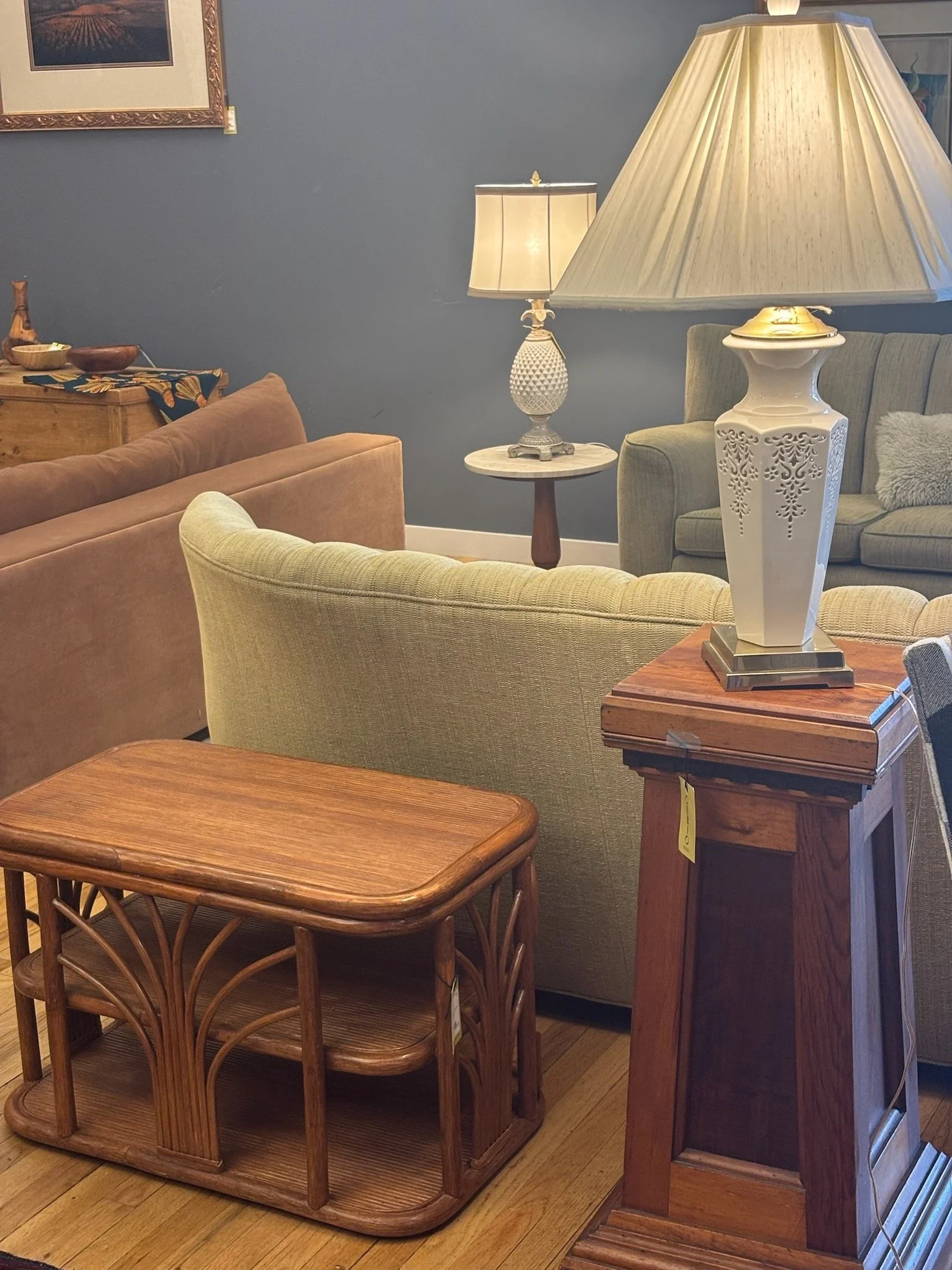 Living room with a green couch, a beige armchair, a wooden coffee table, two table lamps, and a wooden sideboard with decorative bowls and vases on top.