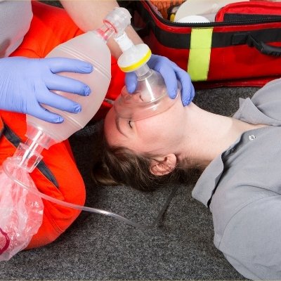 Emergency responder providing oxygen to a person using a bag valve mask.