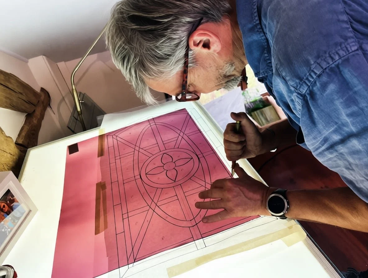 Stained glass artist cutting glass for a traditional lead came window during the restoration of a reclaimed farm door window