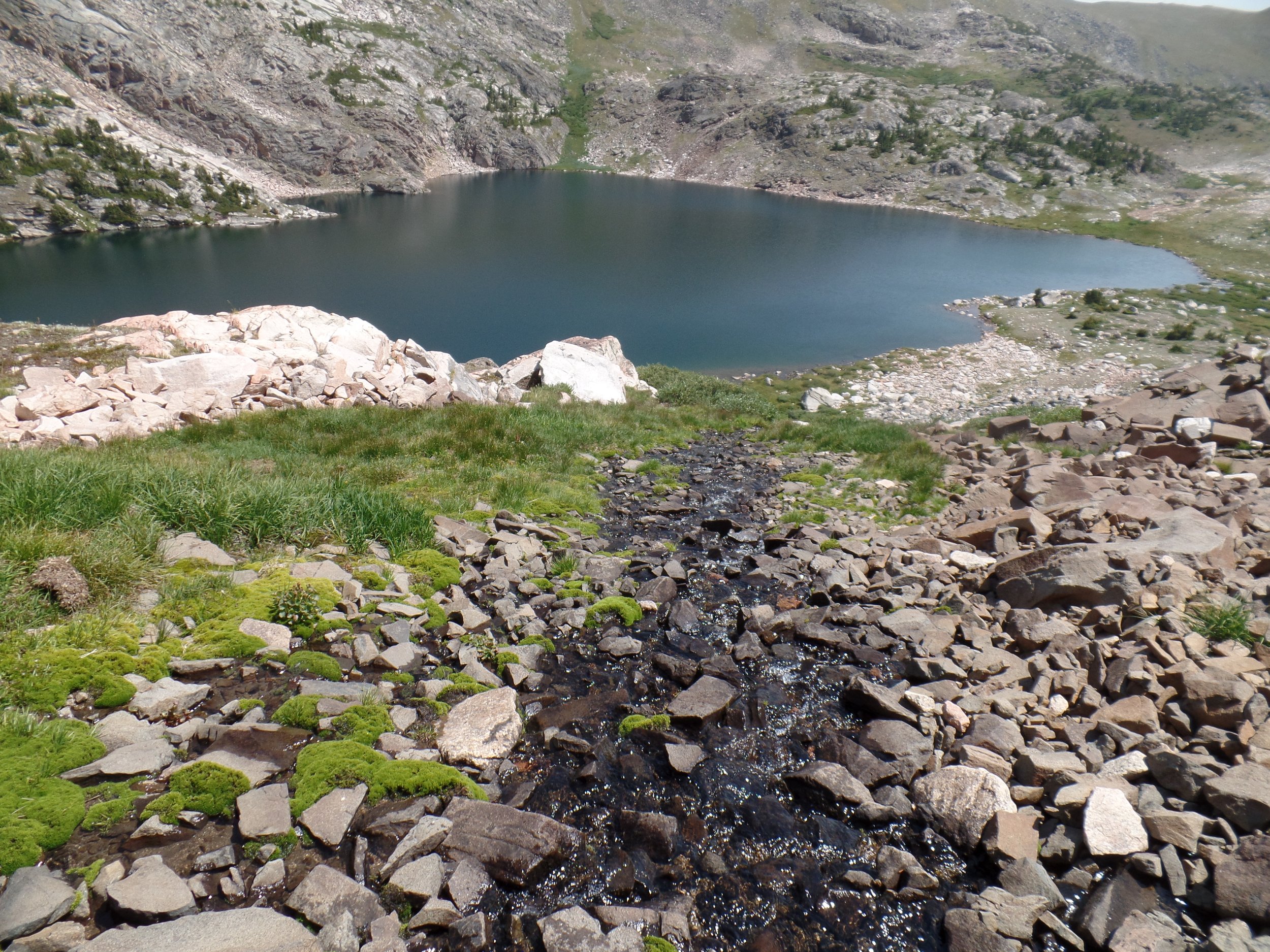Mountain lake with rocky terrain, moss, and clear blue water